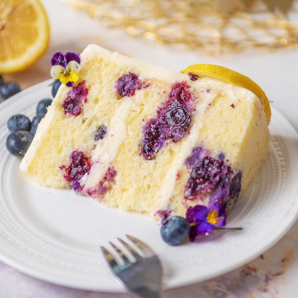 closeup of lemon blueberry cake slice on a white plate