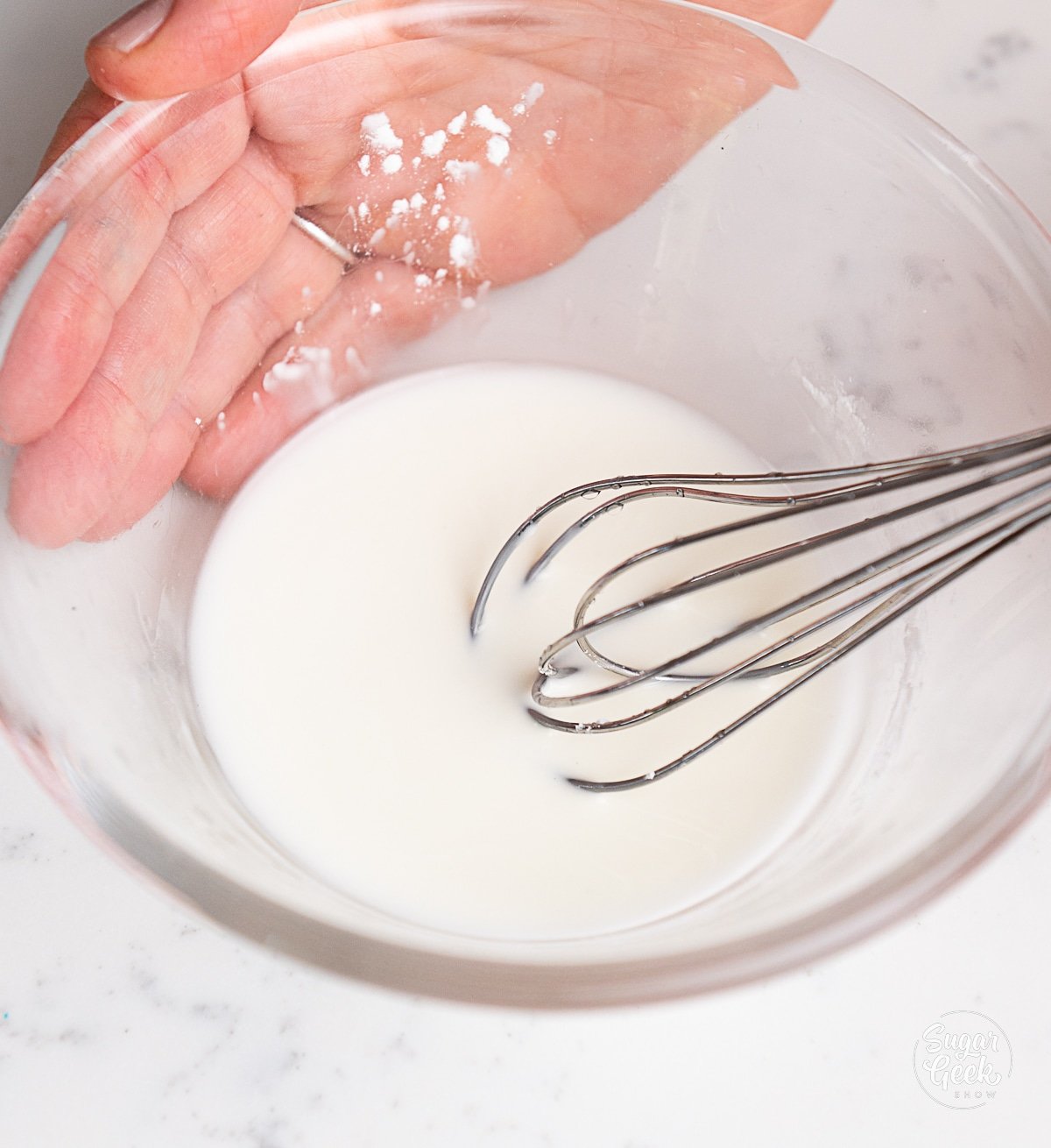 hands whisking water and cornstarch together.