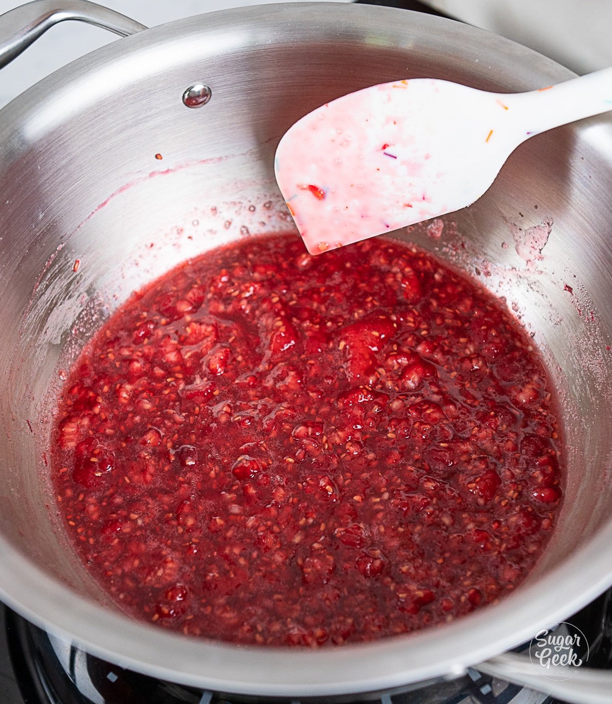 cooked raspberries in a pot with a spatula.