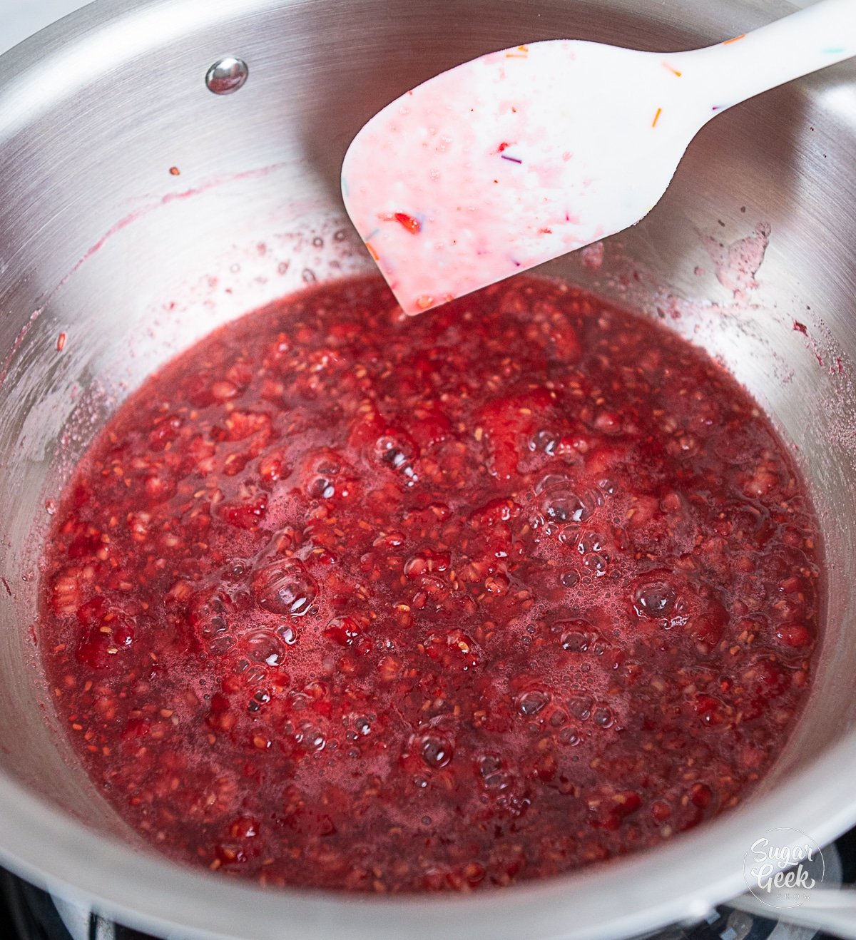 raspberries bubbling while being cooked in a pot.