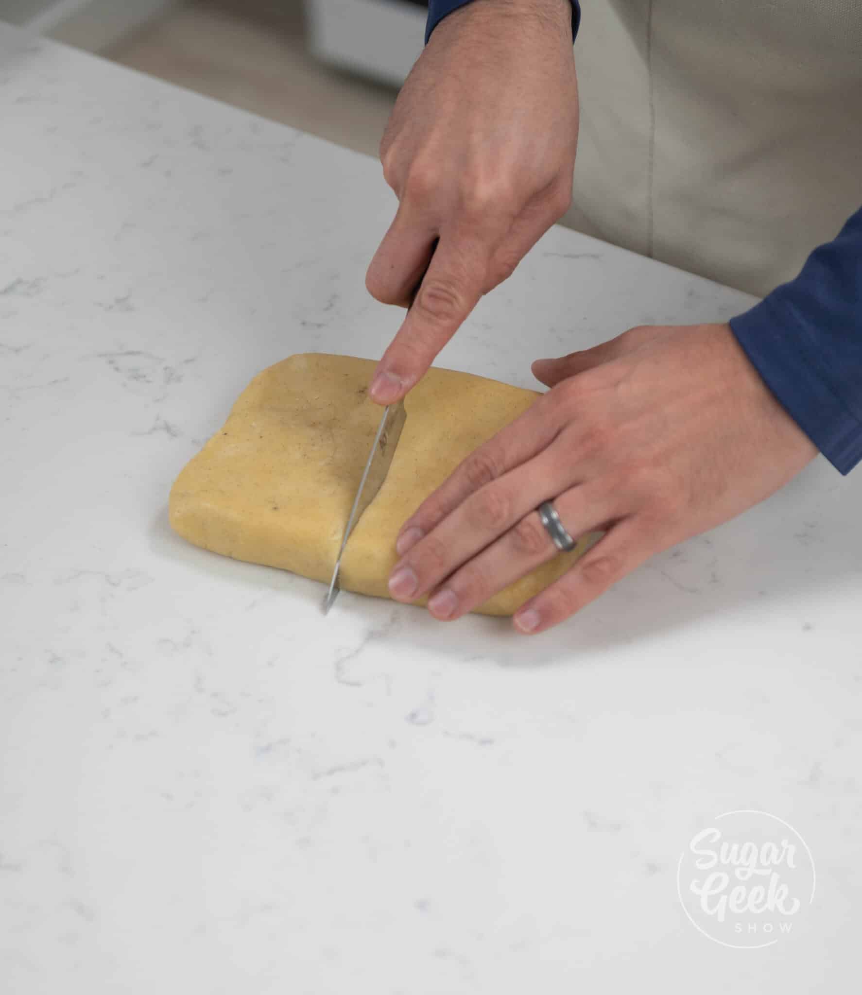 hands using a knife to cut tart dough in half.