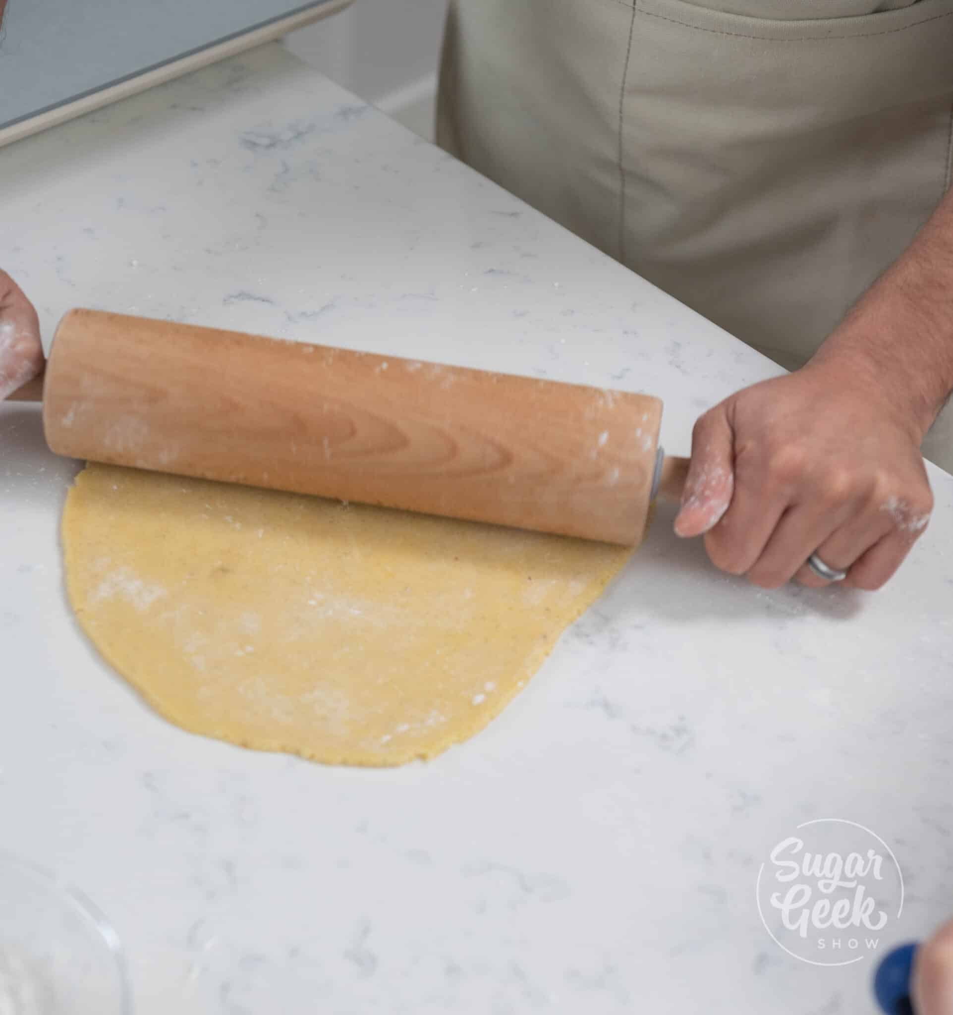 hands using rolling pins to roll dough.
