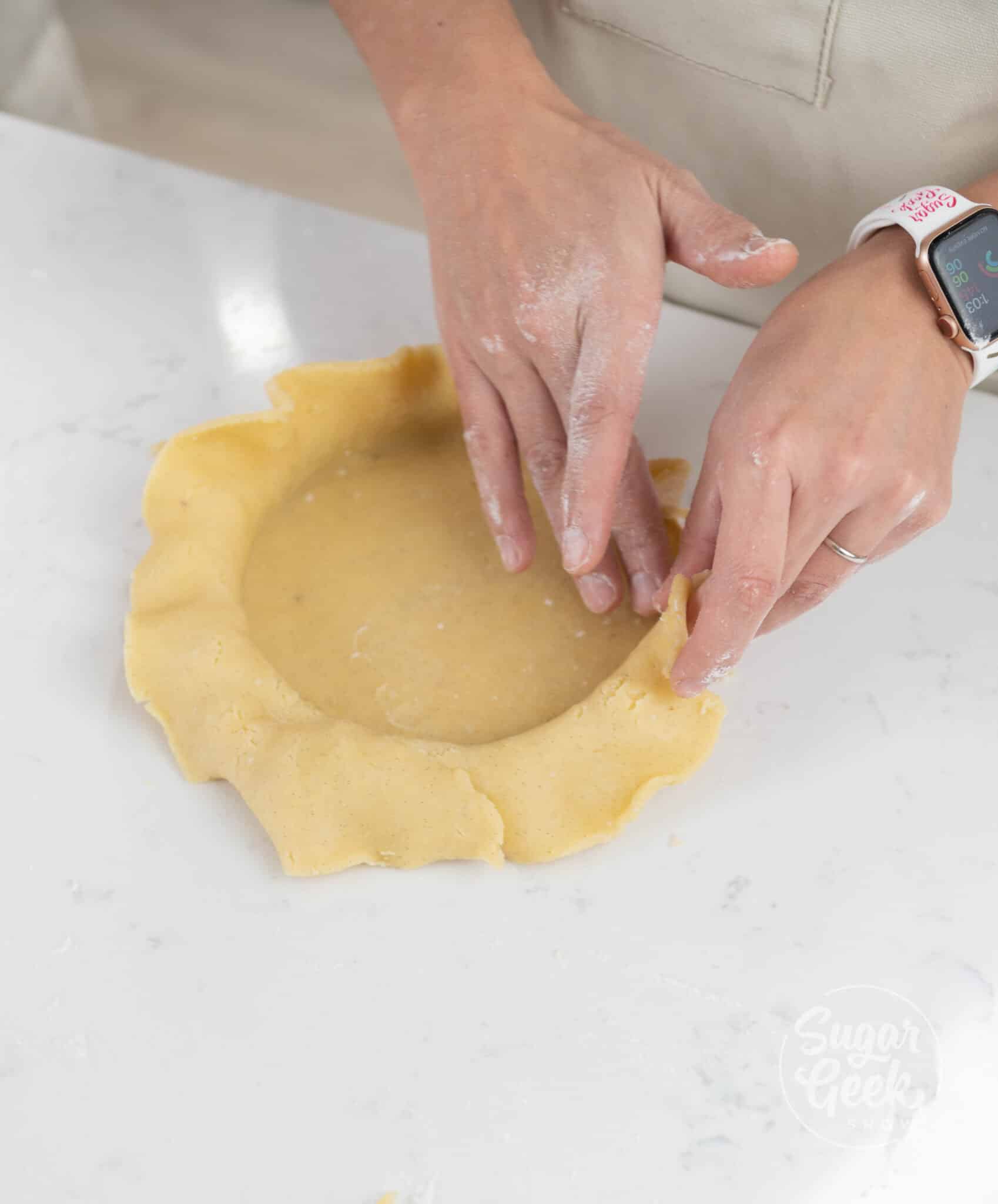 hands firmly pressing dough into tart shell.