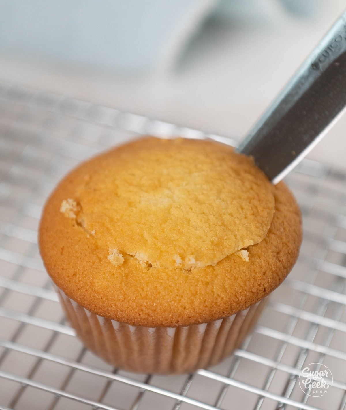 knife cutting center out of a yellow cupcake.