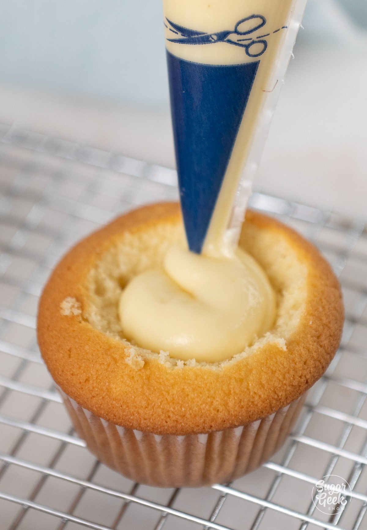 piping filling into center of a yellow cupcake.