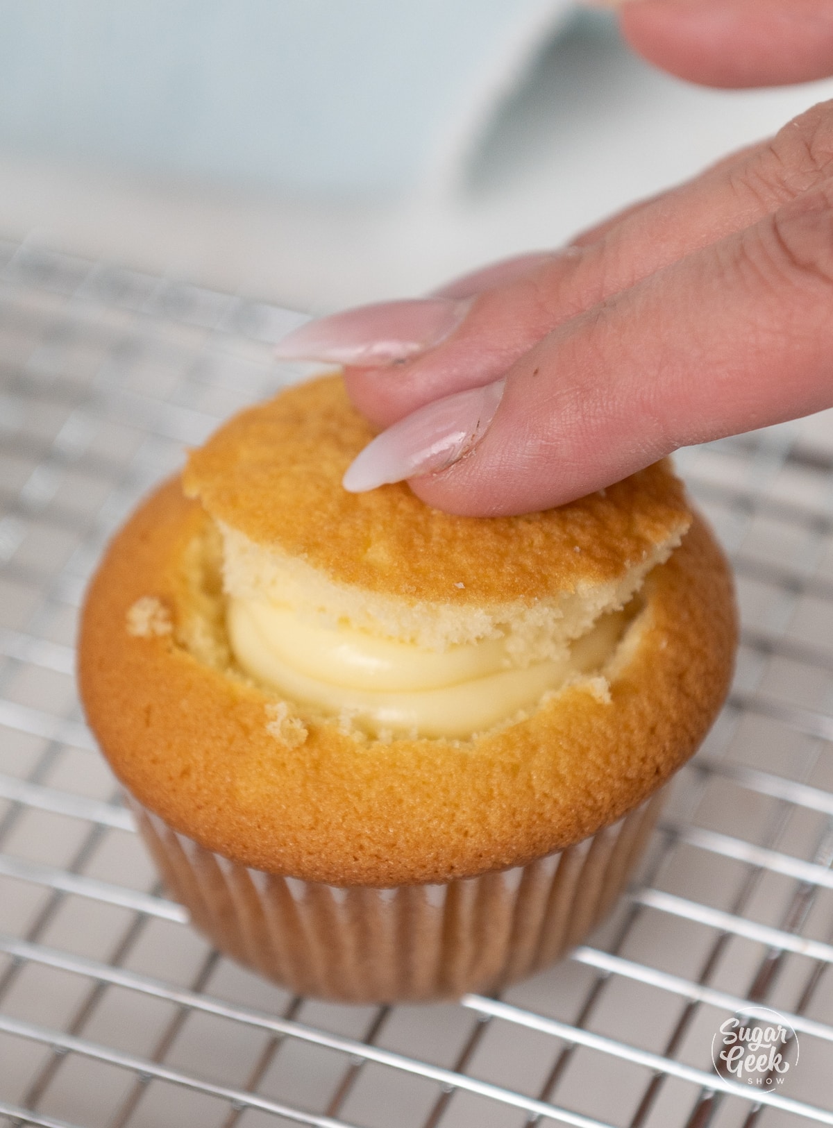 Hand placing top back on filled yellow cupcake.