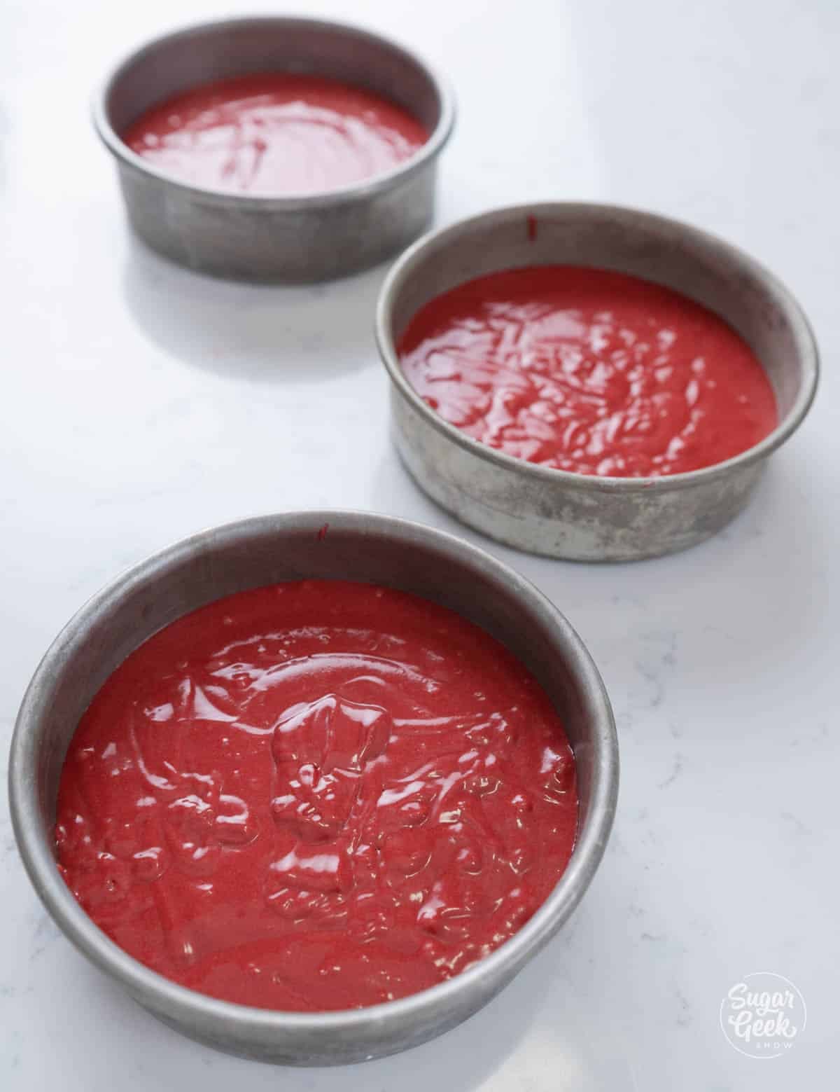 Red velvet cake batter in pans.