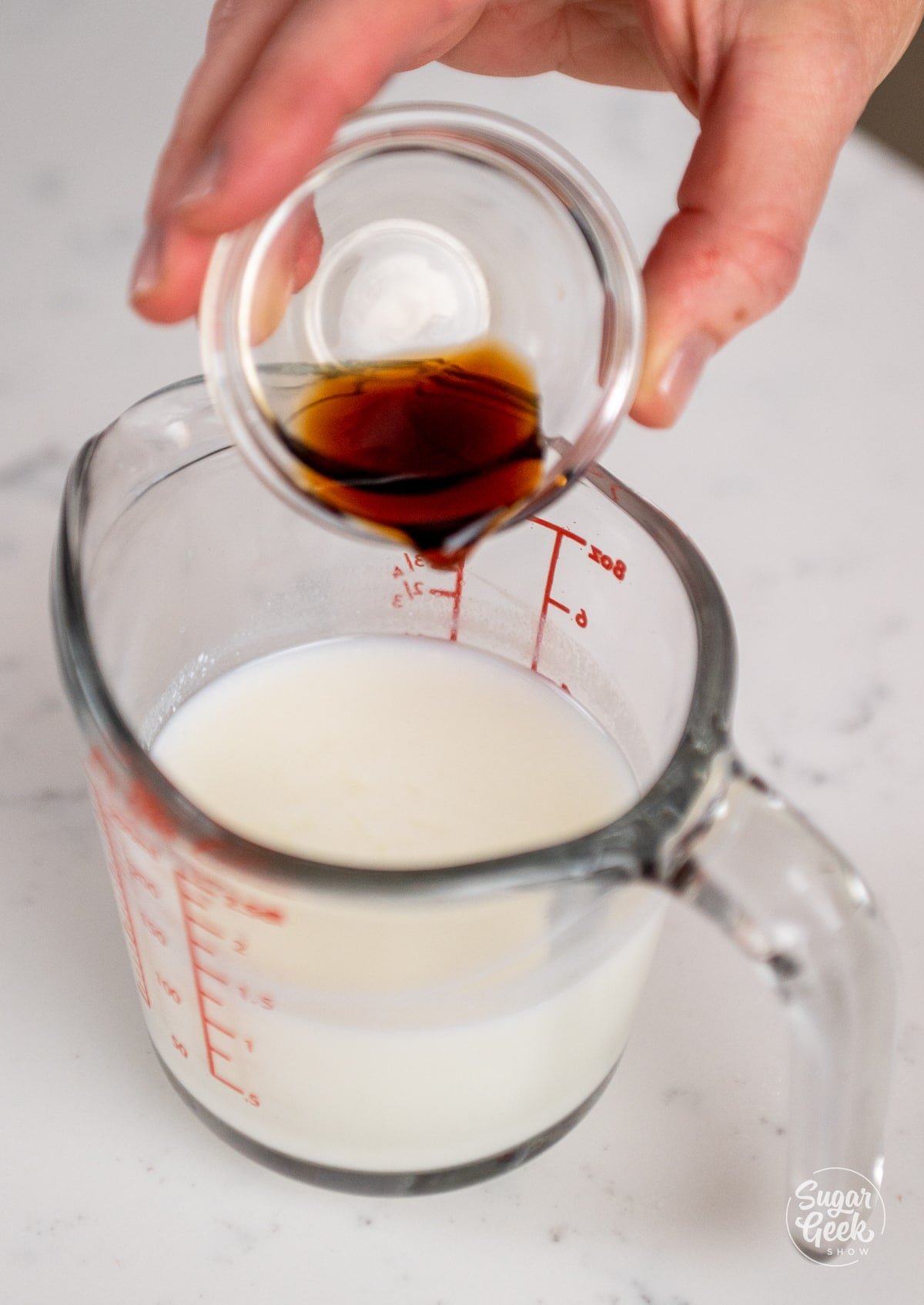 hand adding vanilla to buttermilk in a measuring cup.