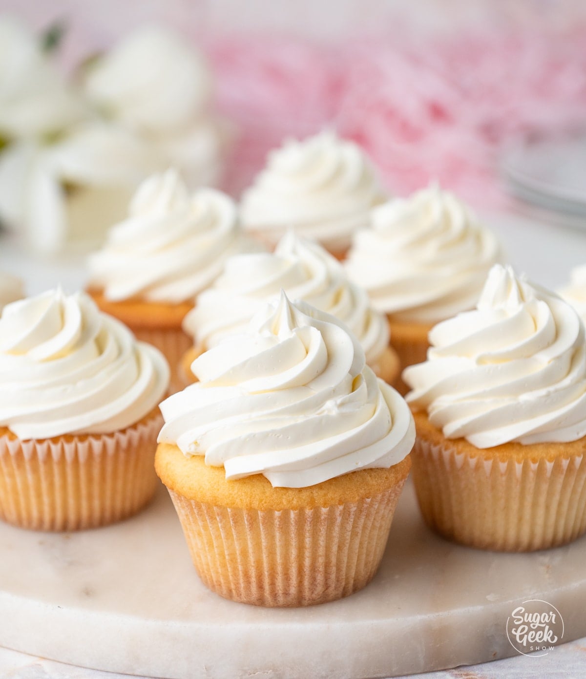 Buttercream frosting piped onto baked vanilla cupcakes. 