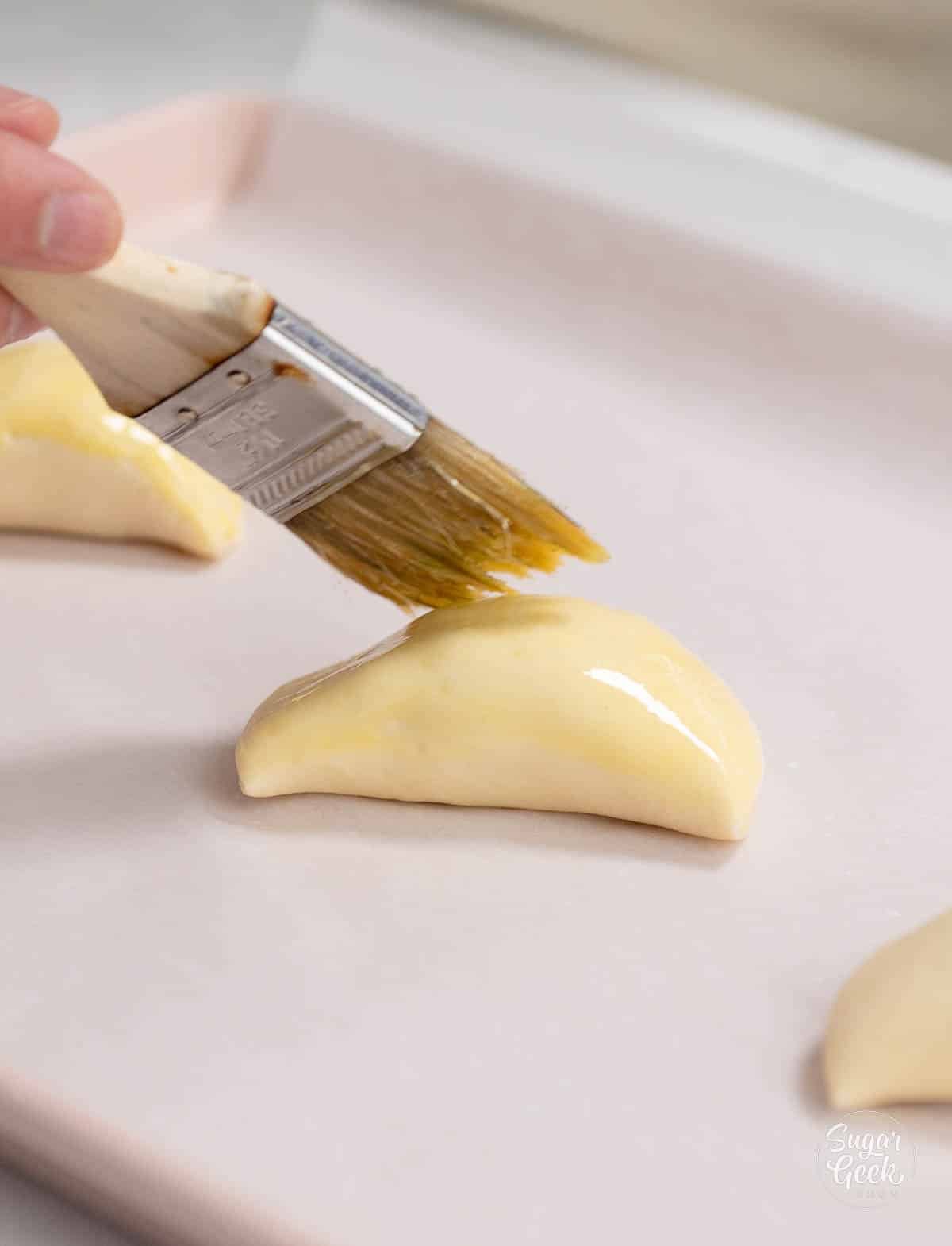 hand using a pastry brush to brush turnover with egg wash.