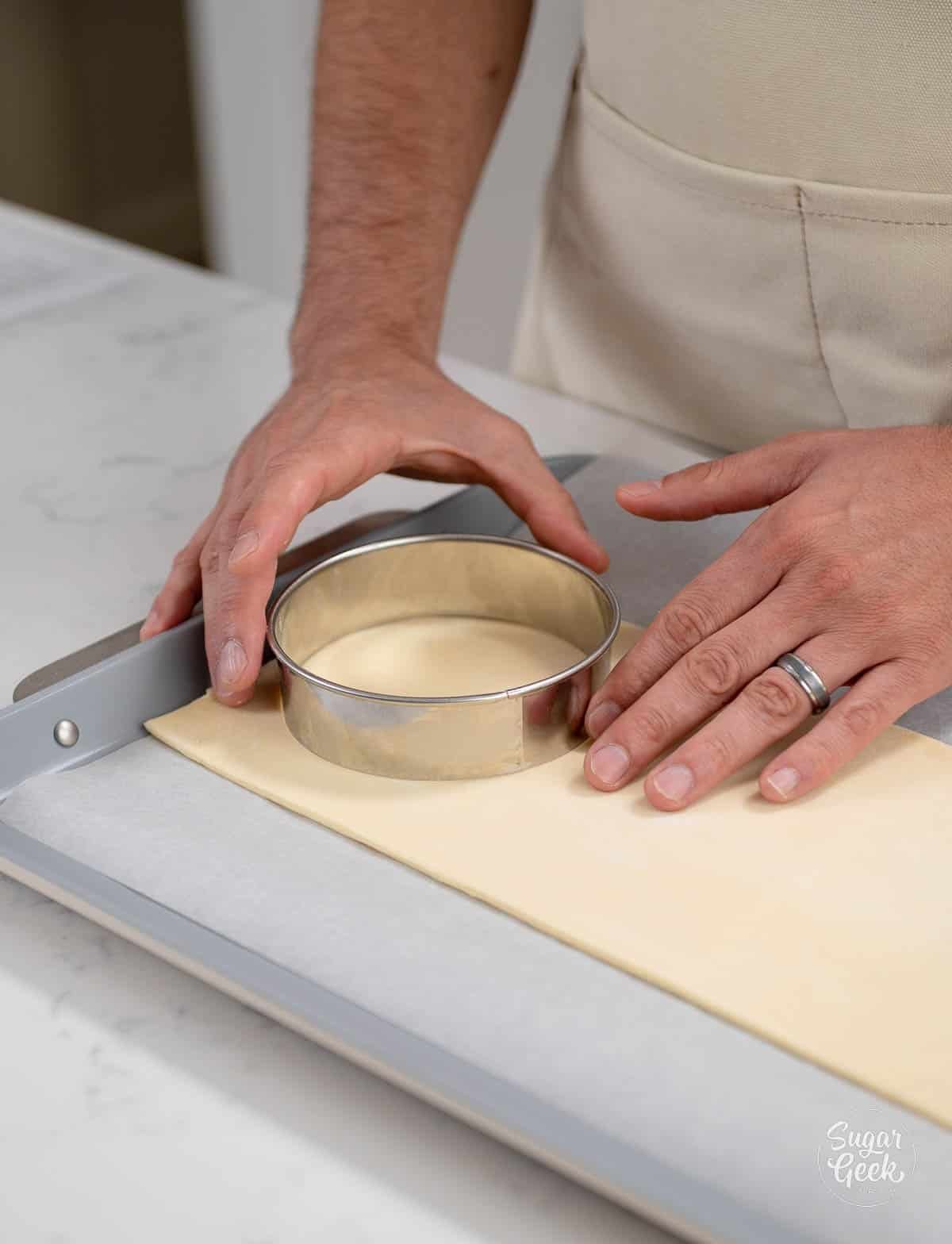 hand cutting circles with a cutter out of dough.