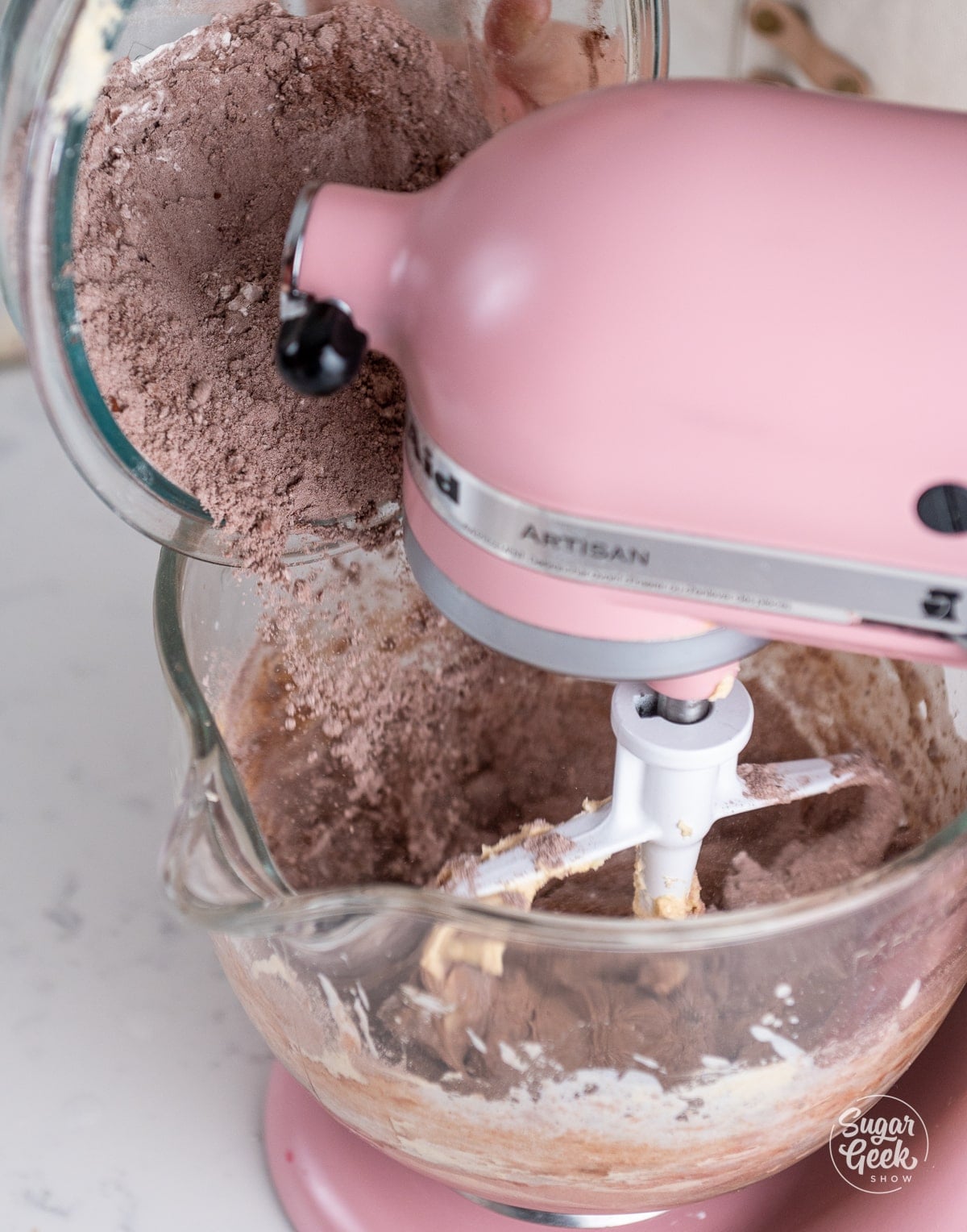 flour and cocoa powder mixture being added into the cupcake batter in the stand mixer