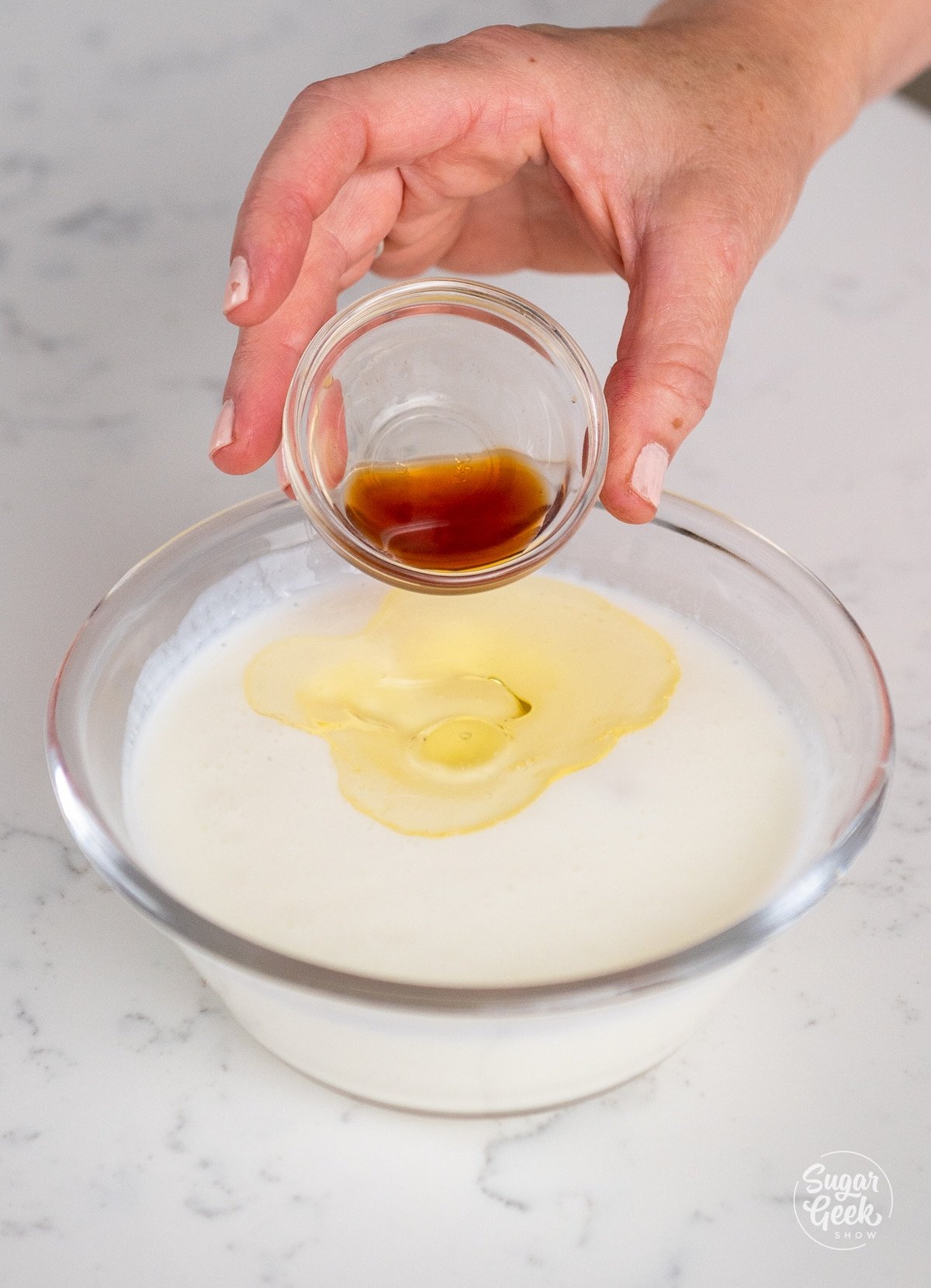 hand pouring vanilla into bowl with buttermilk and oil. 