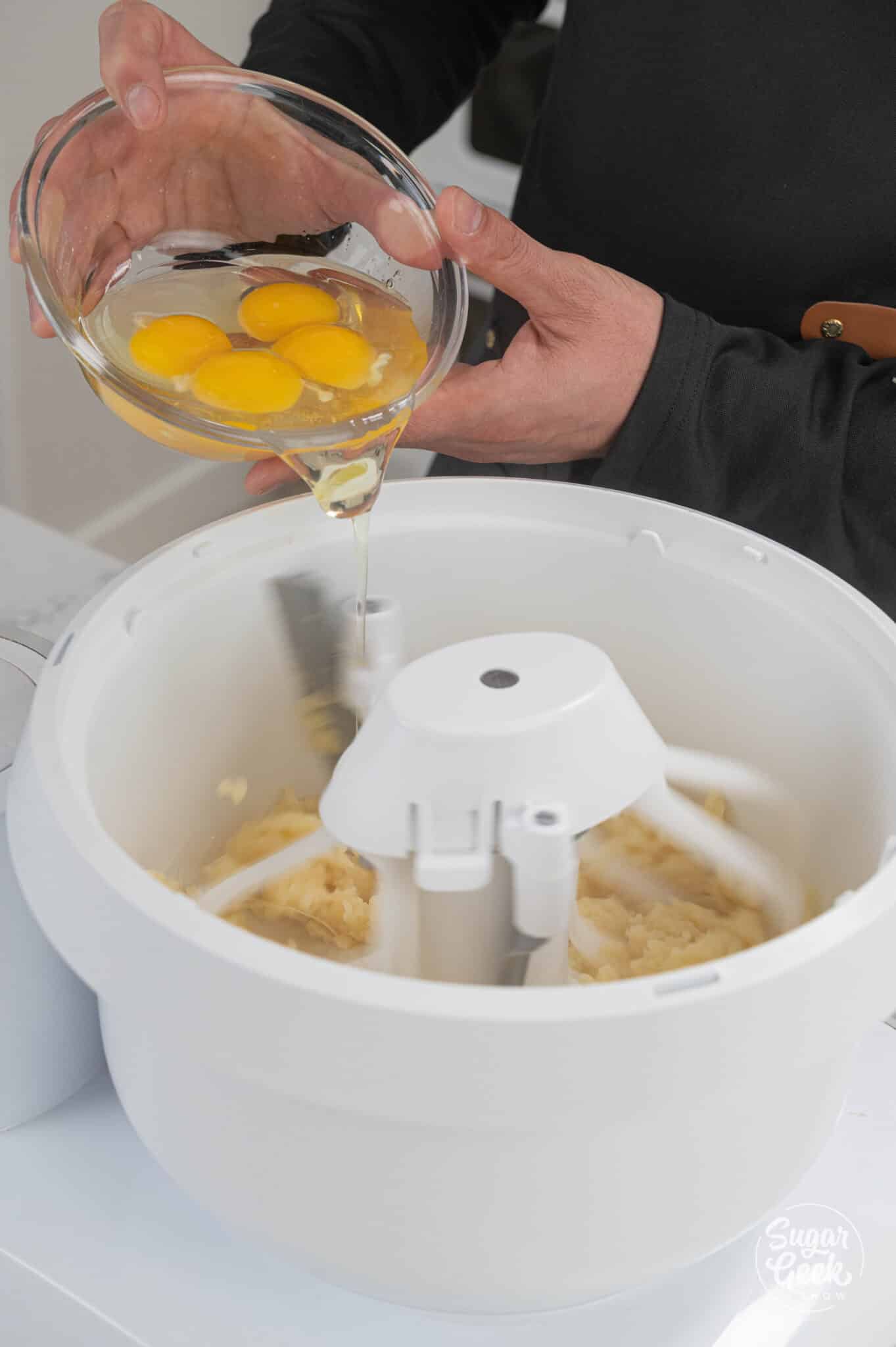 pouring eggs into pâte à choux in a stand mixer bowl