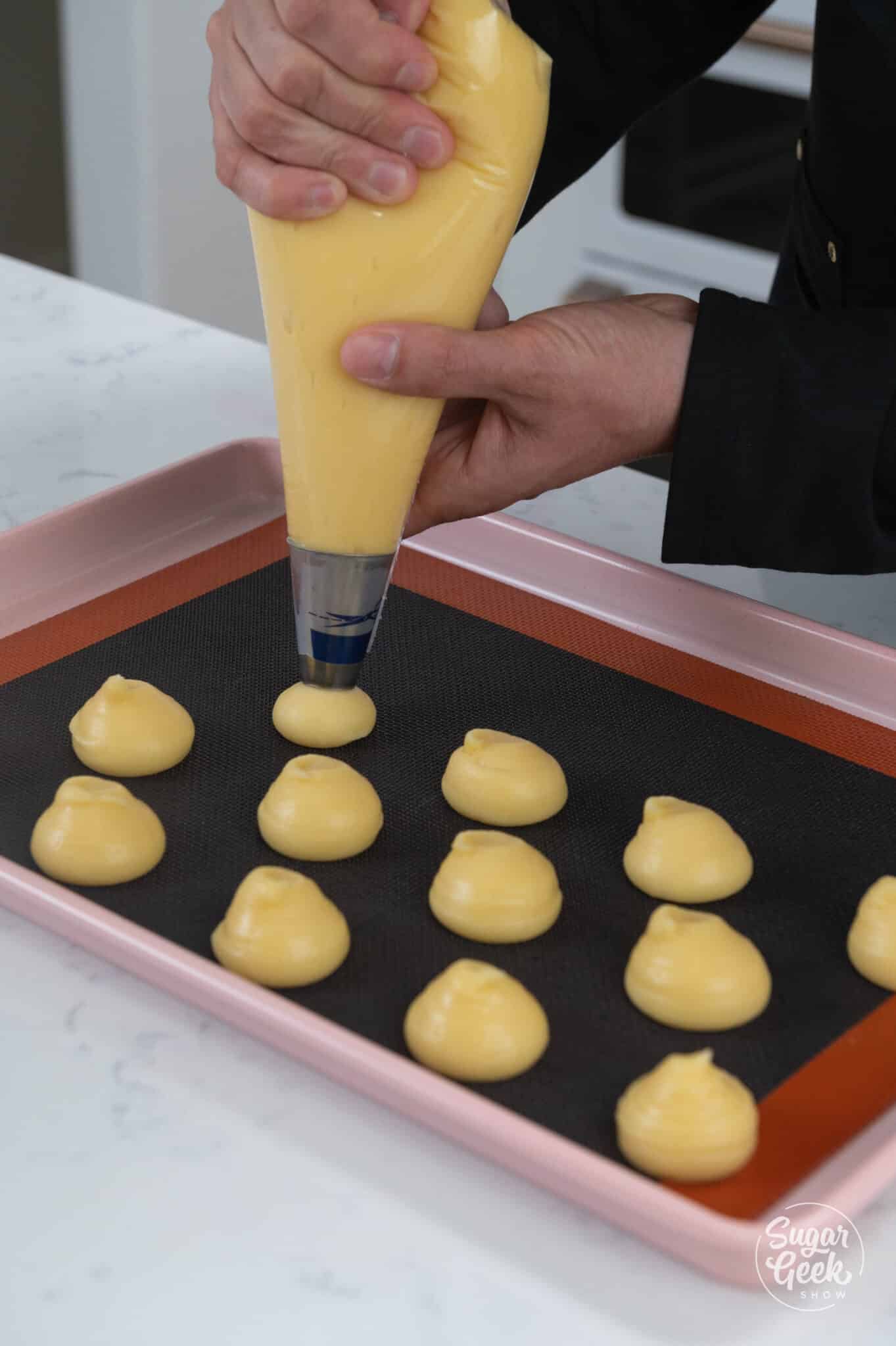 piping cream puff dough onto a baking sheet