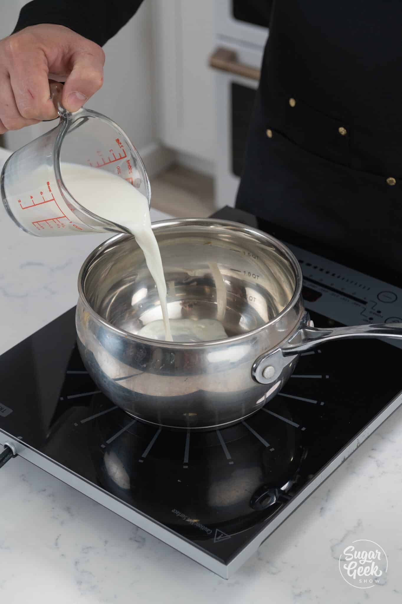 milk pouring into a pot over a stove