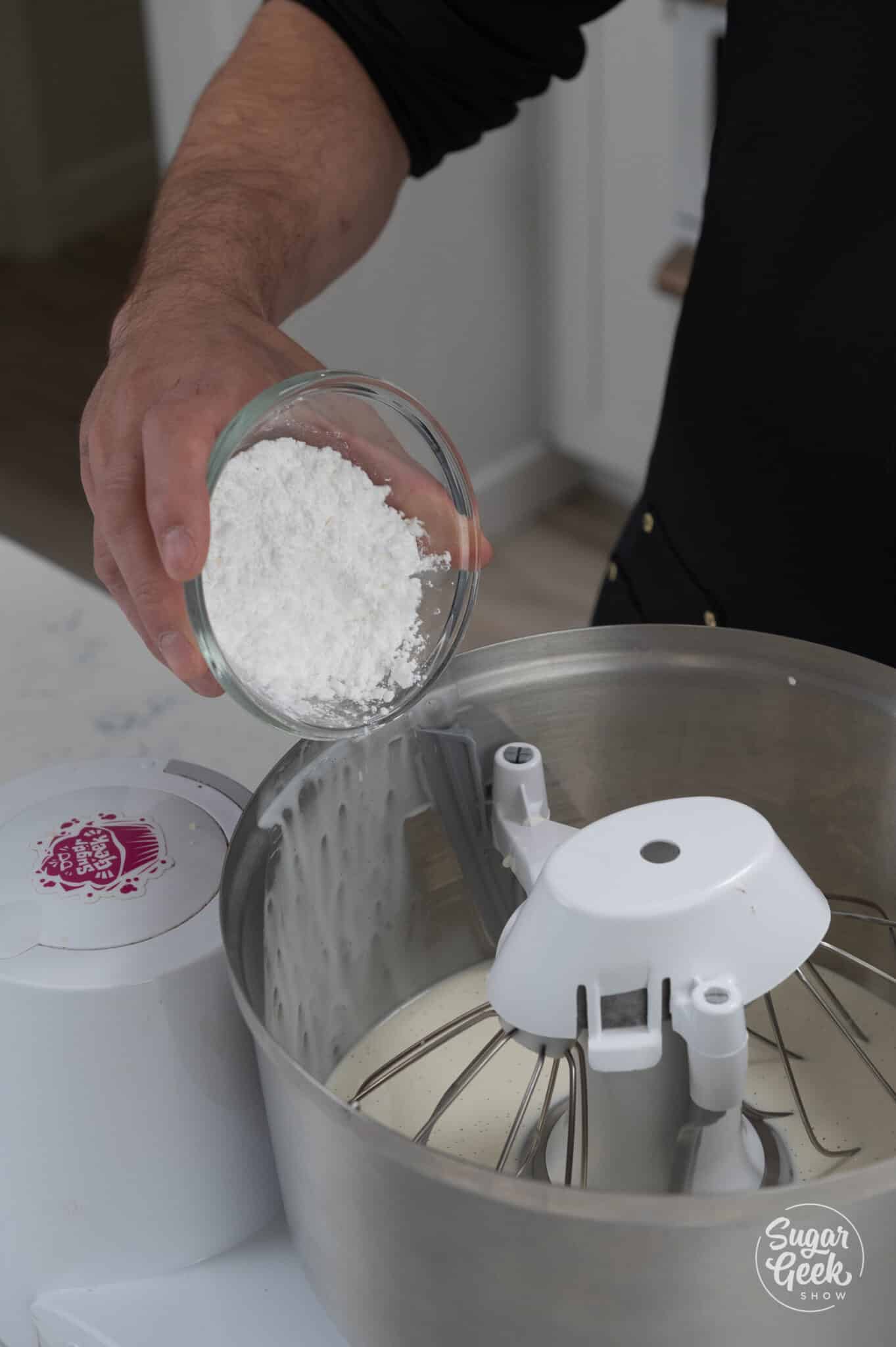adding powdered sugar to whipped cream in a stand mixer bowl