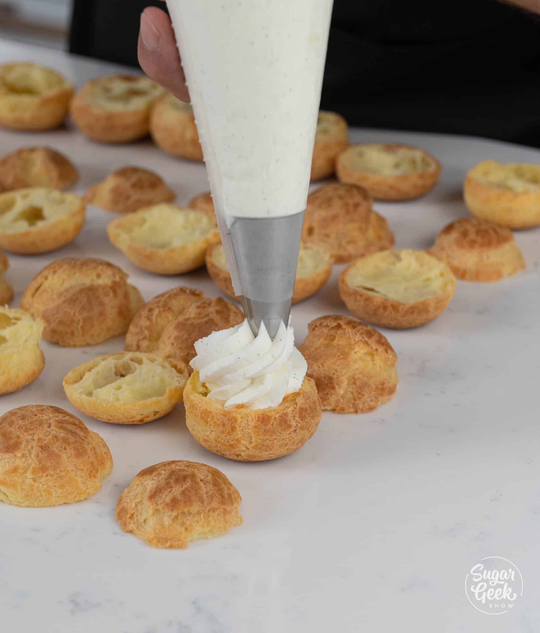 piping bag piping whipped cream onto a cream puff