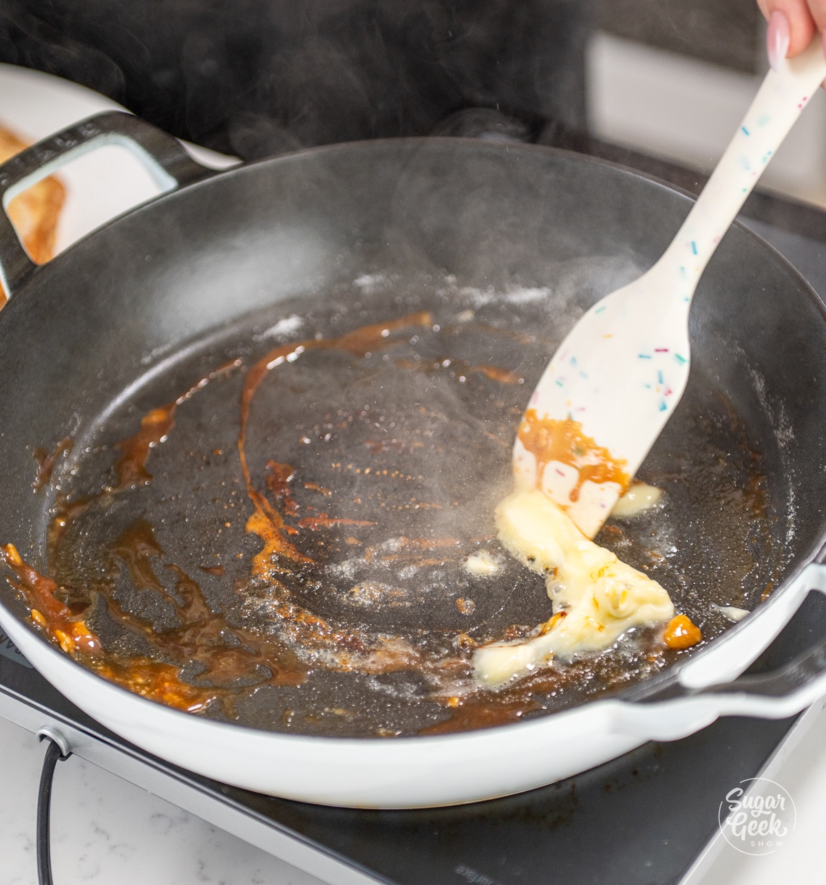 adding butter to a skillet of caramel