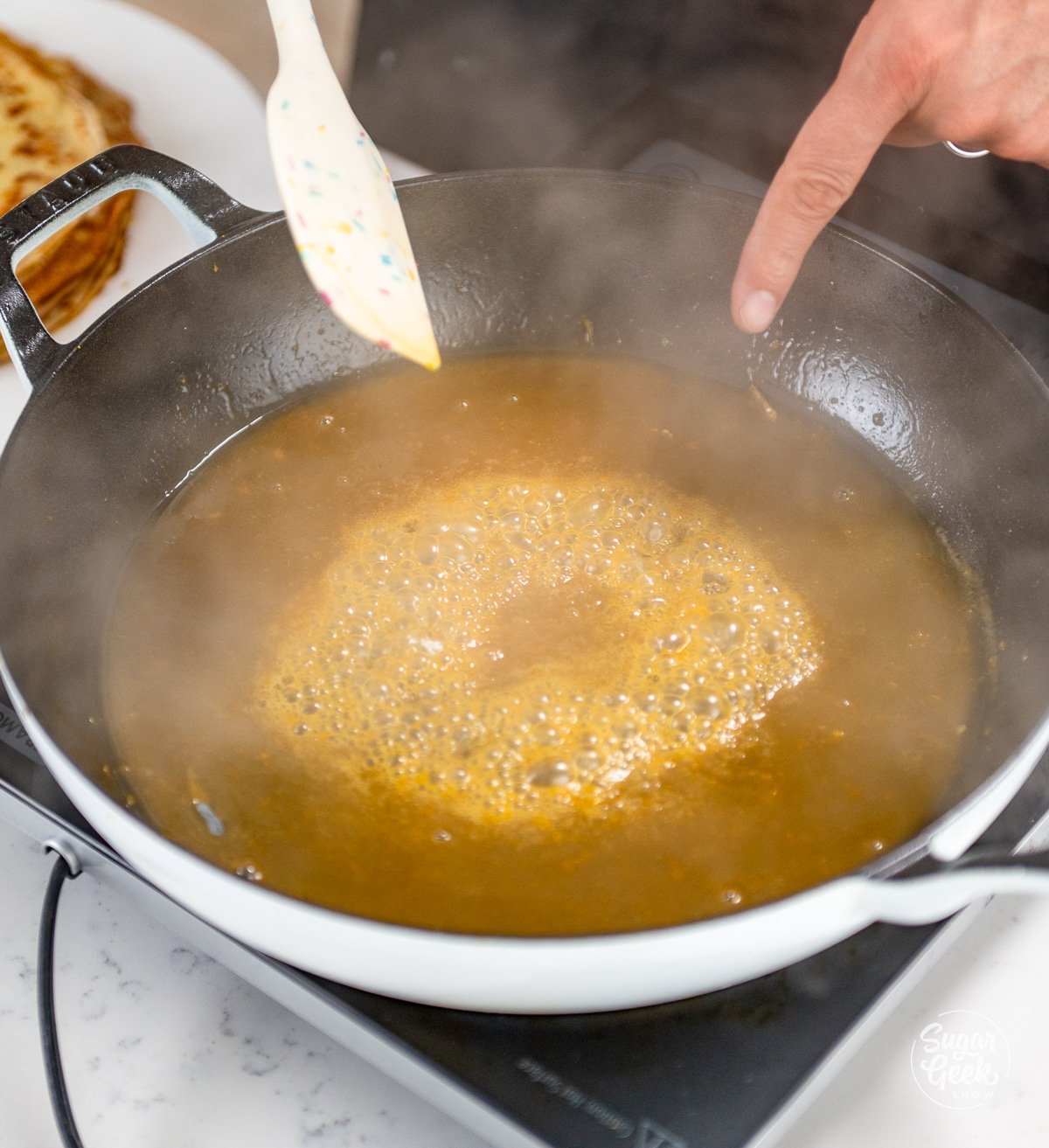 reducing orange sauce in a skillet