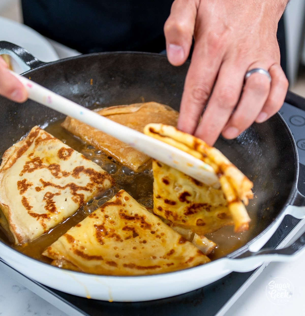 flipping over crepes in an orange sauce