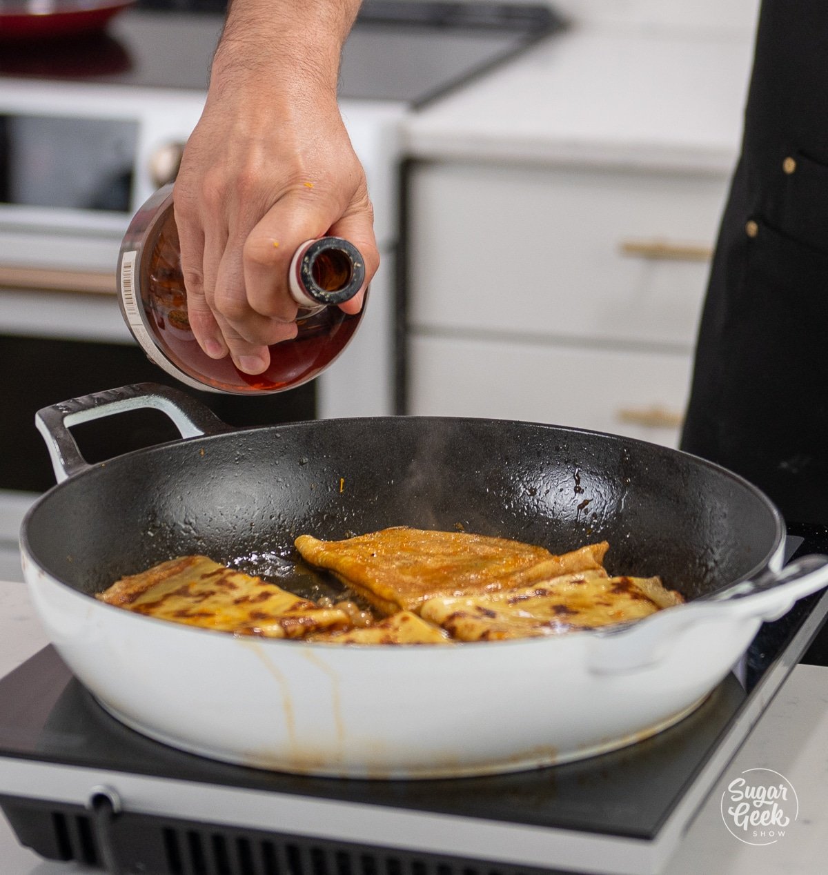 adding grand marnier to a skillet of crepes