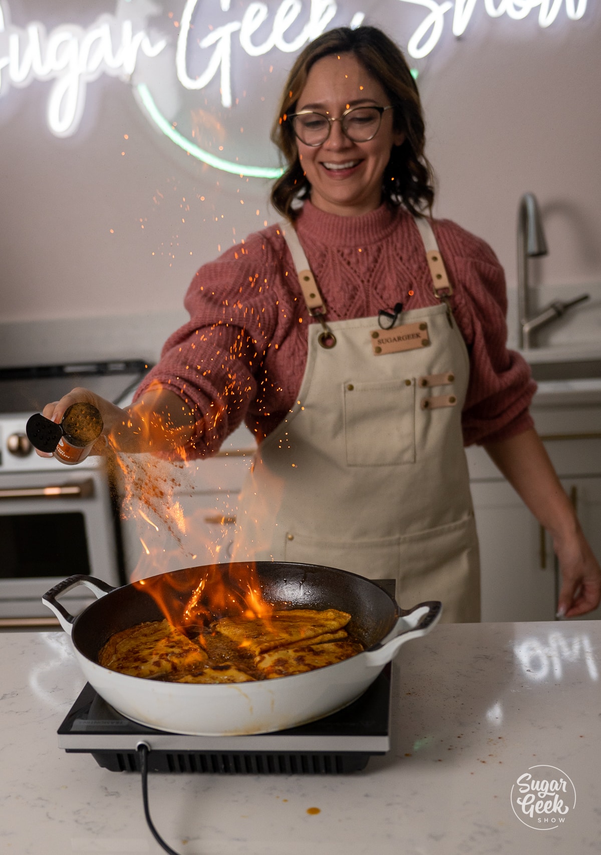 sprinkling cinnamon into fire over a pan of crepe suzette