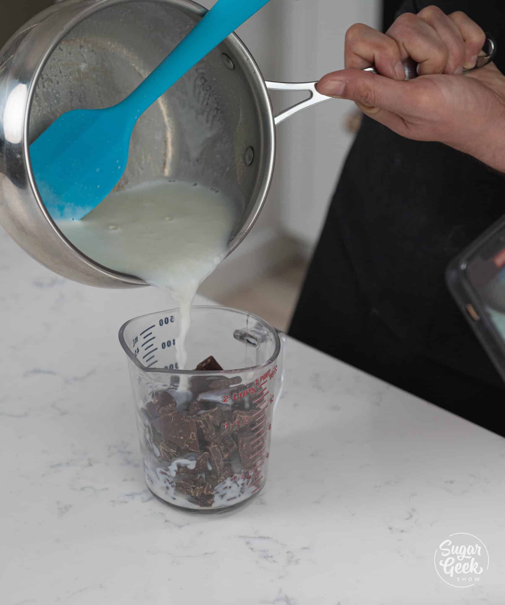 pouring hot milk over chocolate in a mixing cup