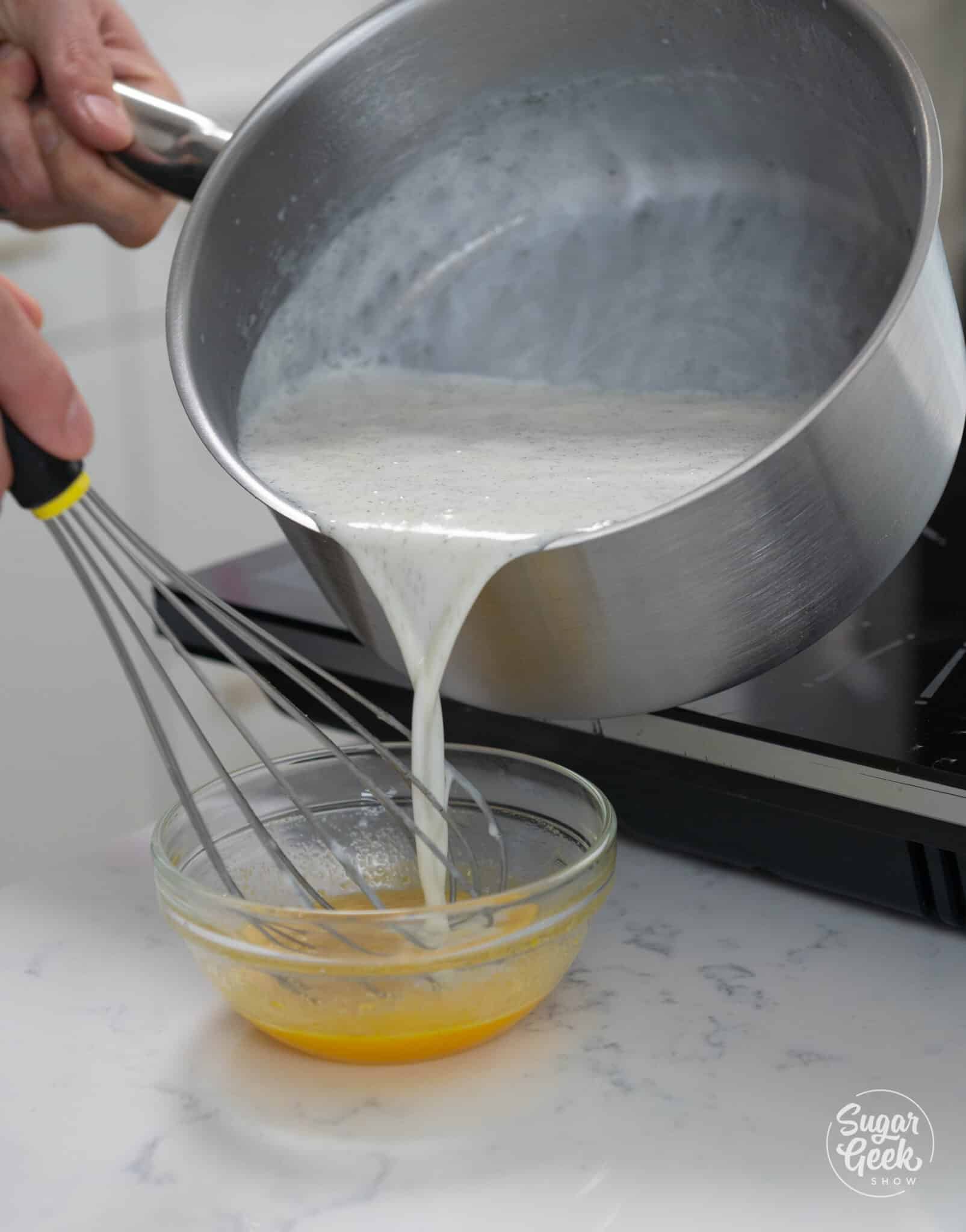 pot of steaming milk being poured into a small bowl of eggs