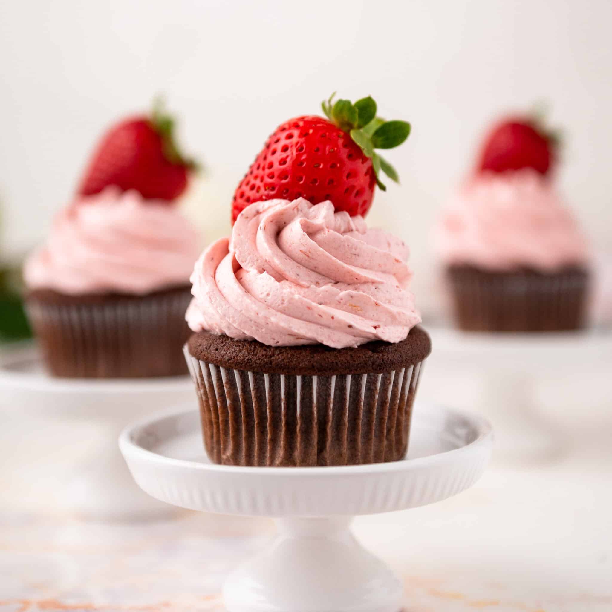 close up of a chocolate cupcake with strawberry buttercream and a strawberry on top