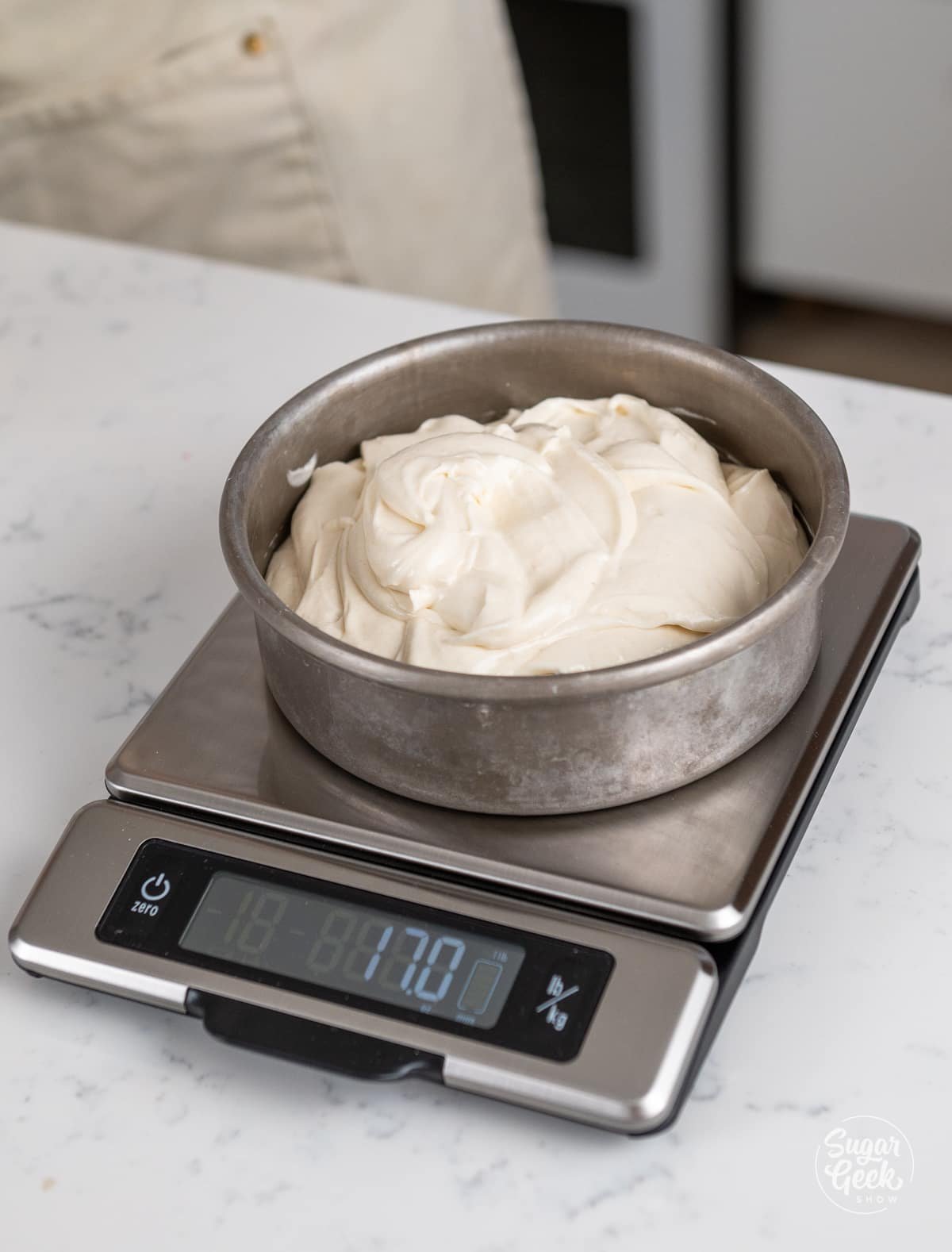 cake pan with cake batter being weighed on a scale. 