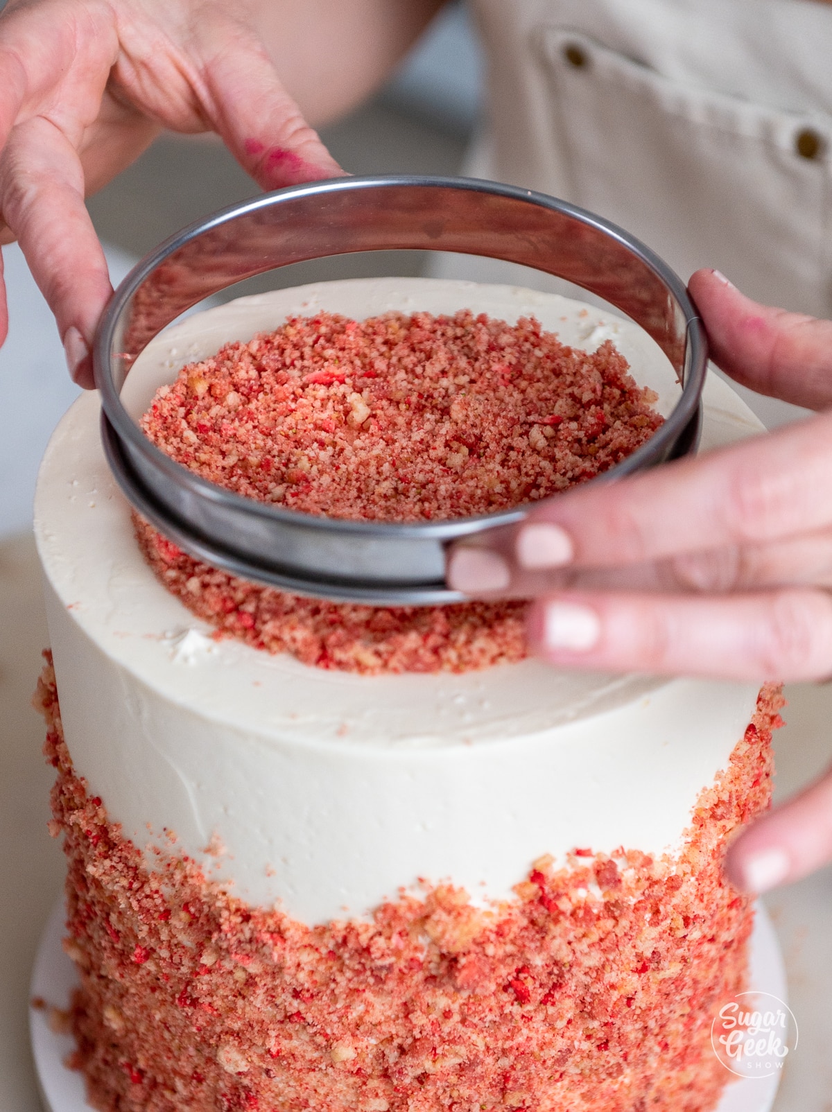 hands removing the ring from the top of the cake. 