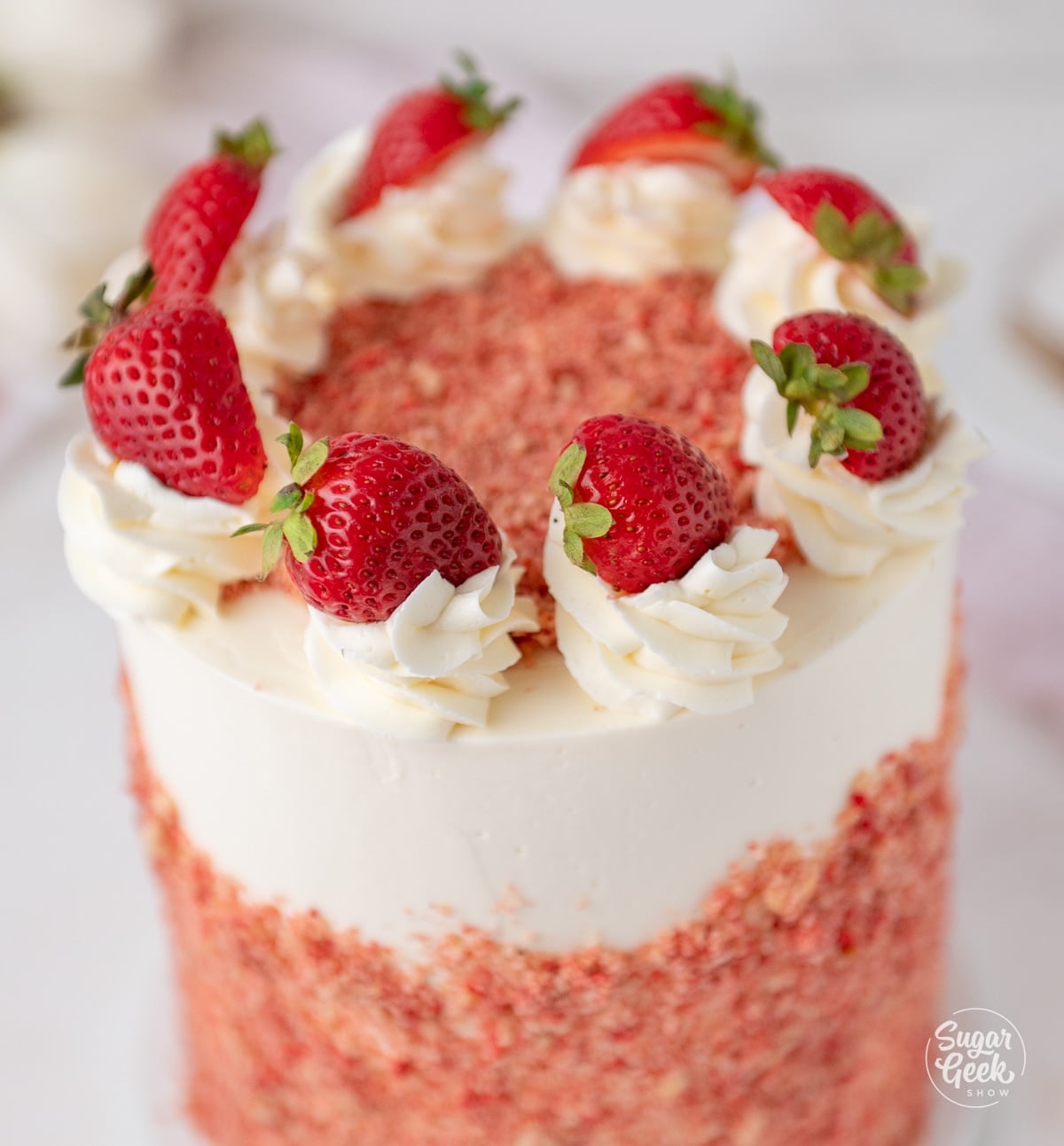 close up of fresh strawberries on swirls of buttercream atop a cake