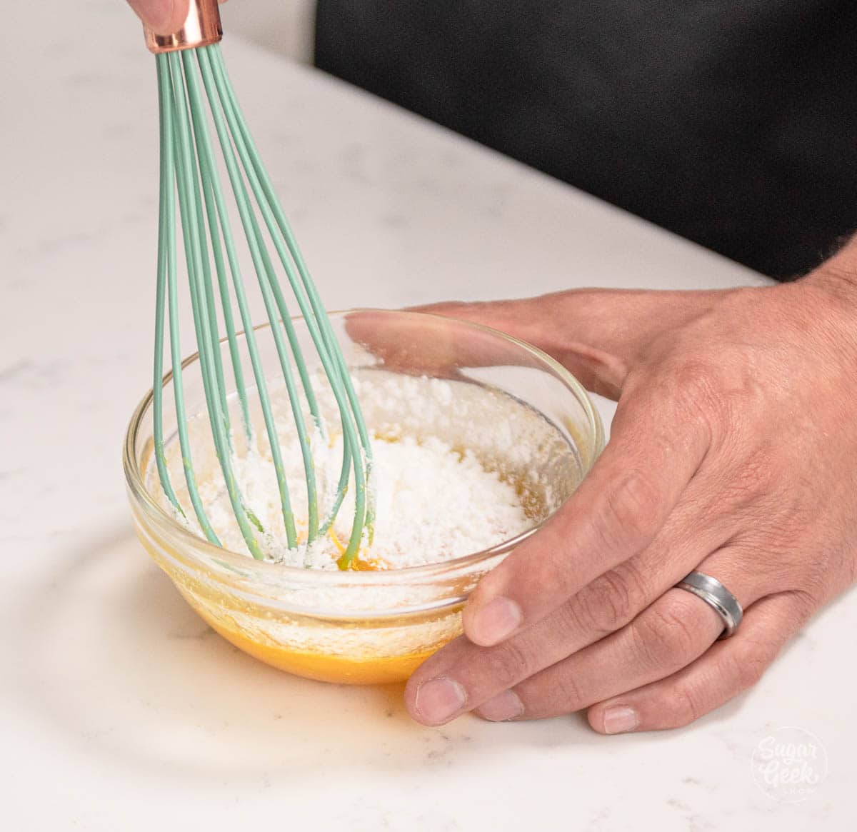 hand mixing cornstarch into eggs in a bowl. 