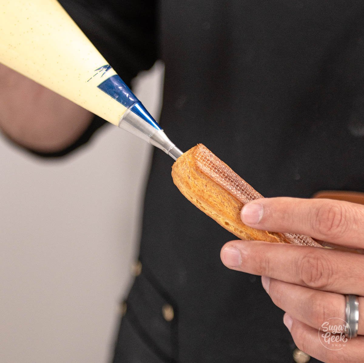 hand filling eclair shell with pastry cream.