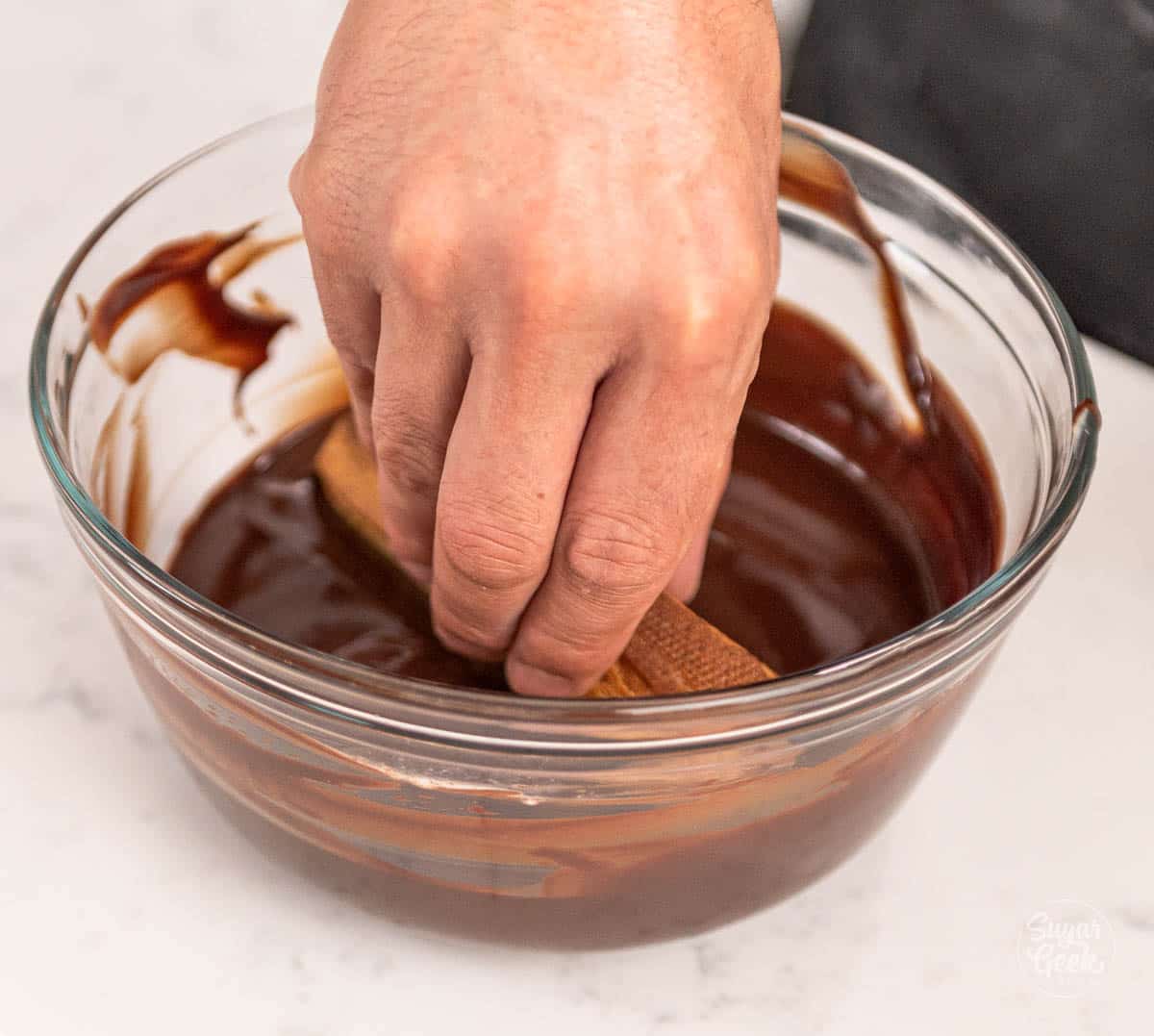 hand dipping eclair into chocolate ganache. 