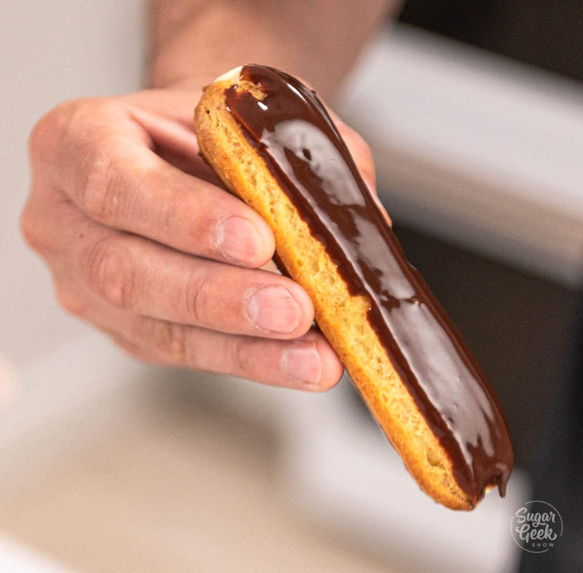 hand with freshly dipped eclair. 