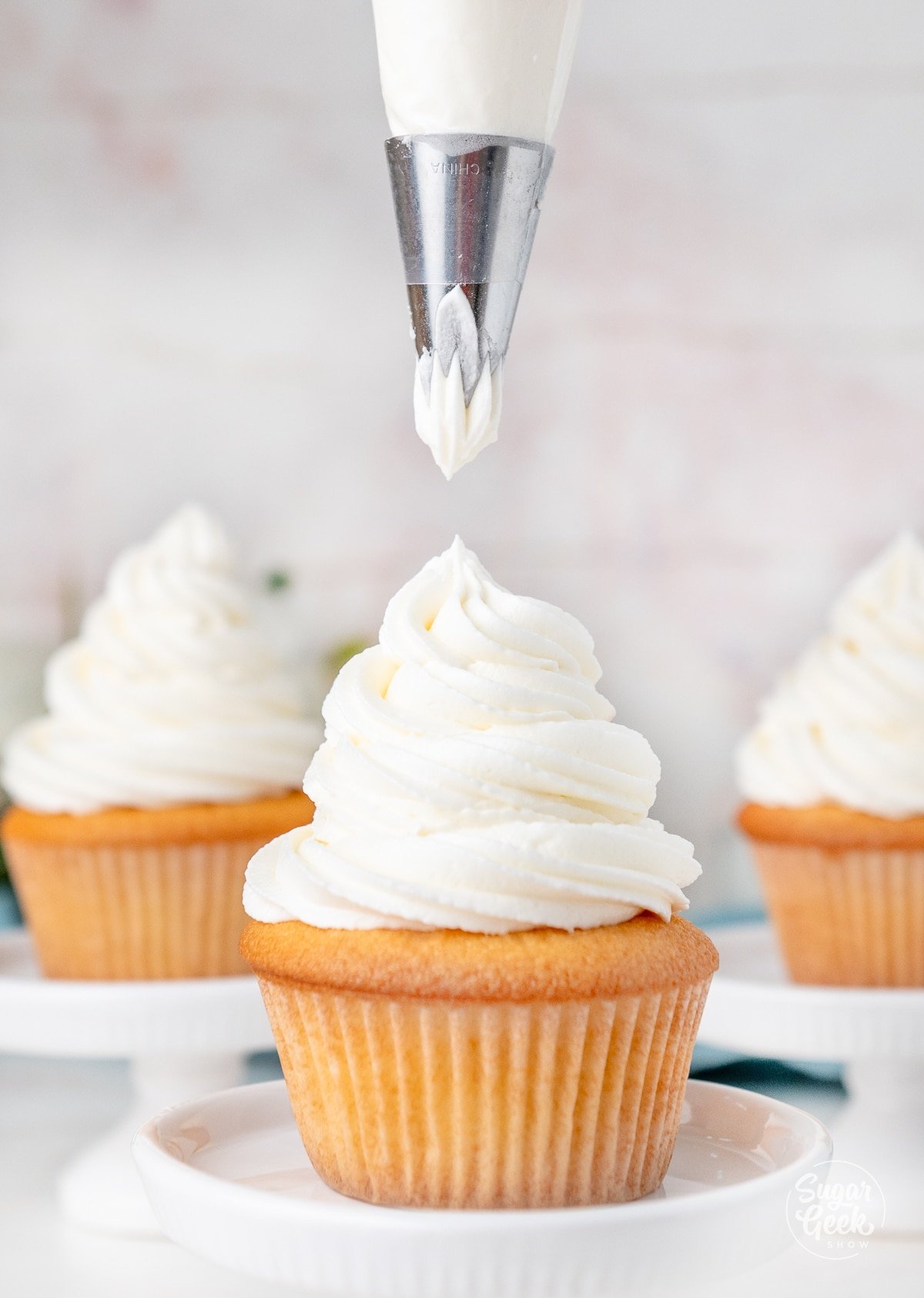 piping american buttercream on a vanilla cupcake.