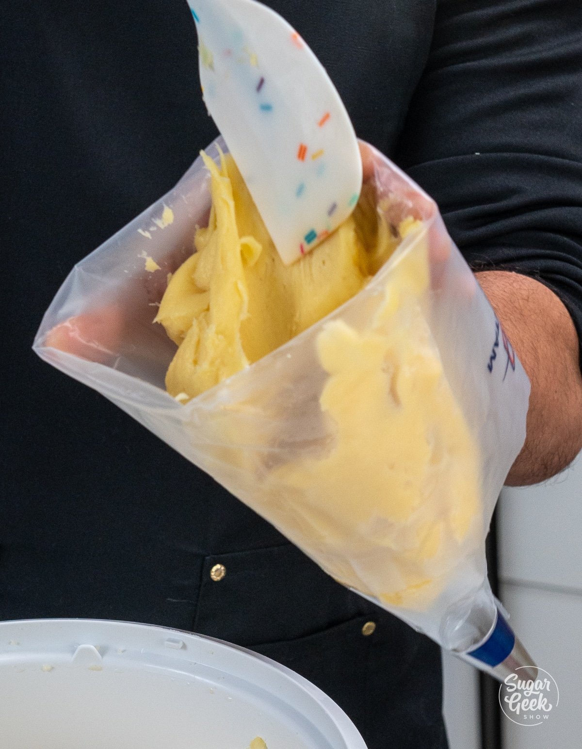 hands holding a spatula to fill a pastry bag with choux dough