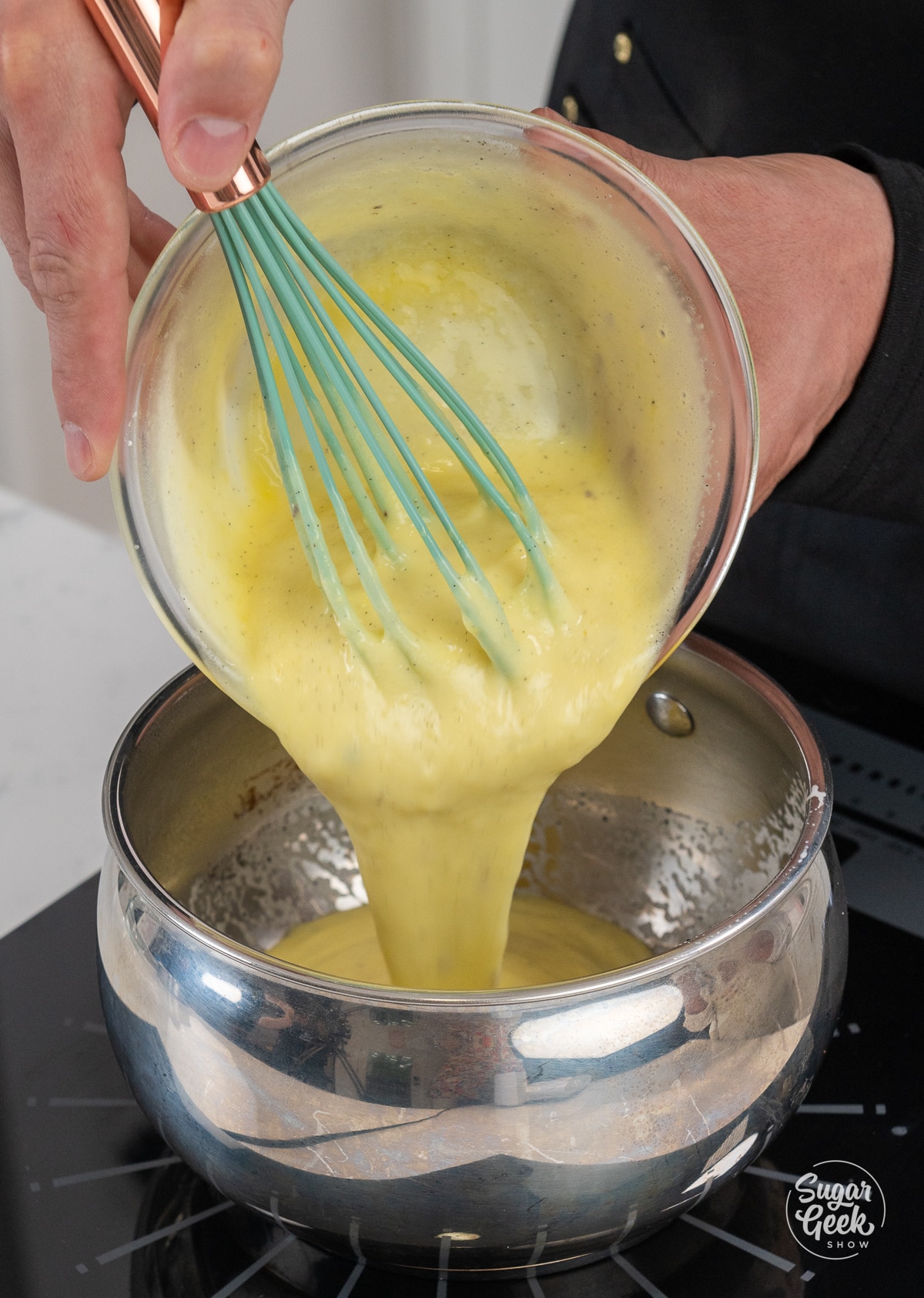 bowl of thin pastry cream pouring back into a metal saucepan