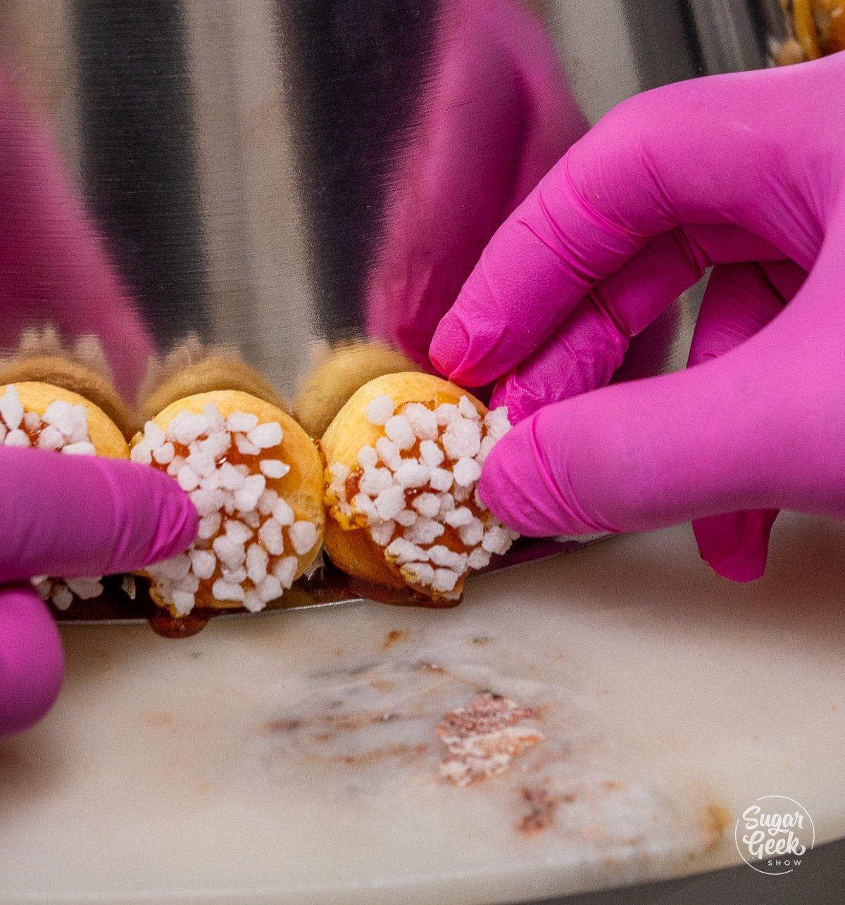 hand assembling cream puffs on the bottom layer of a metal cone
