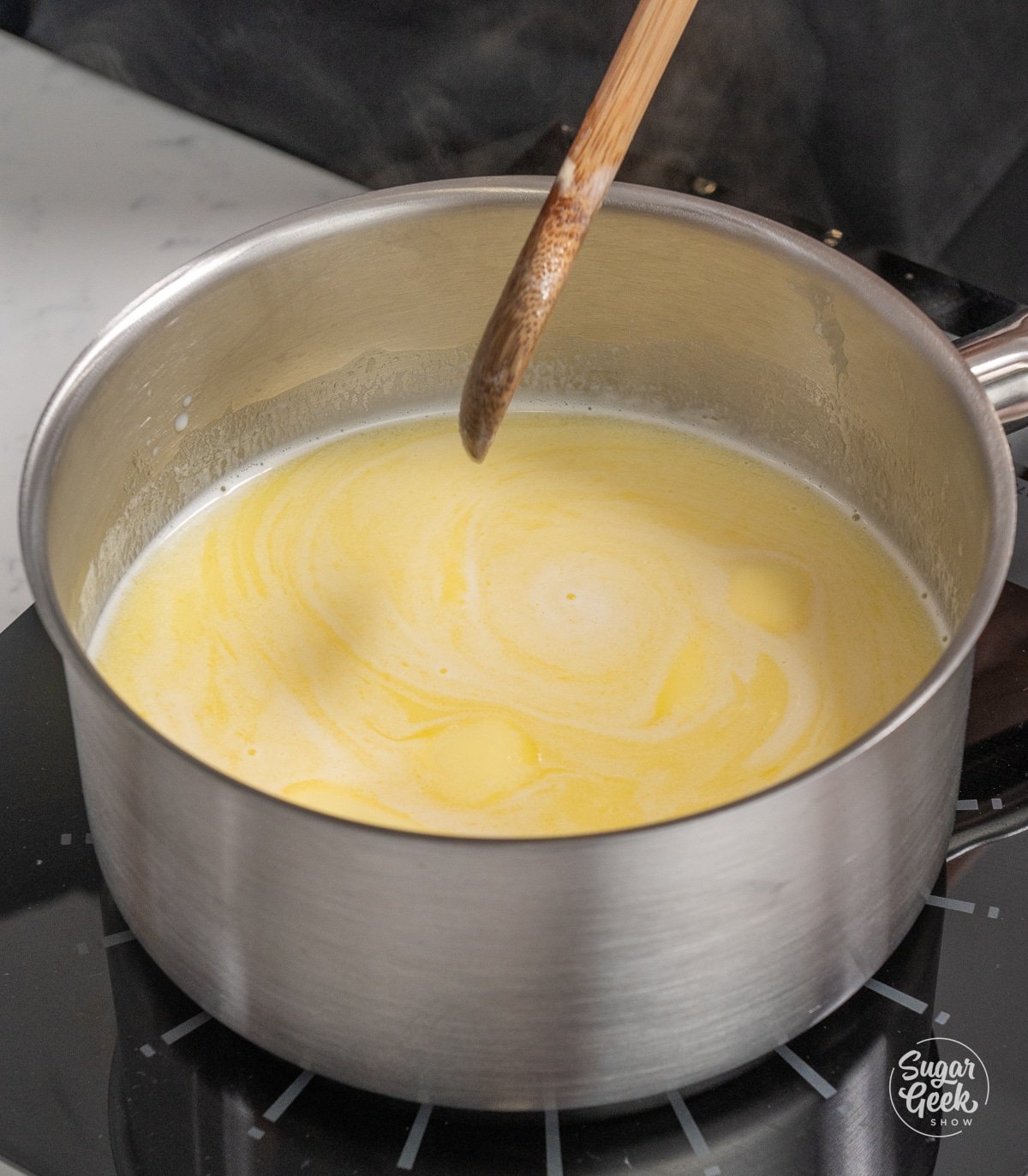 metal pot of melted butter and milk with a wooden spoon