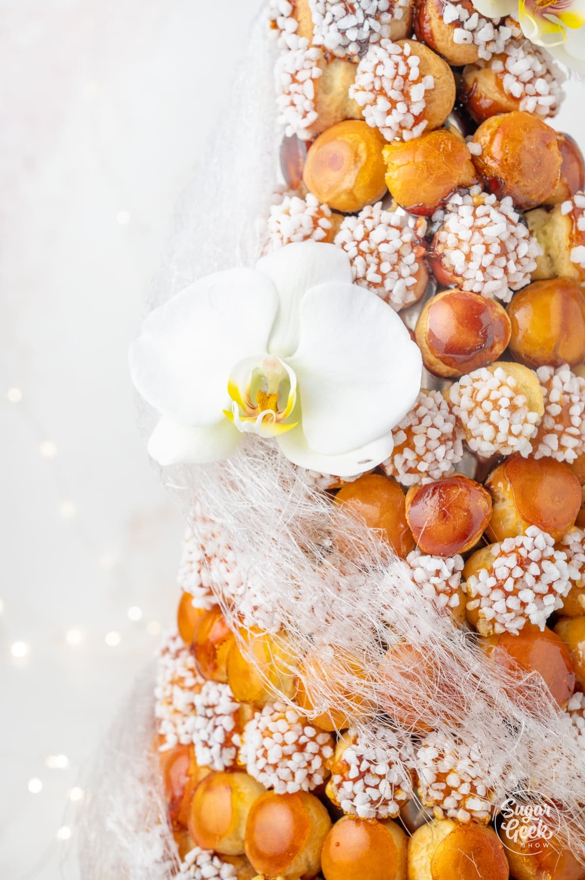 patterned croquembouche with spun sugar and a white orchid on the side