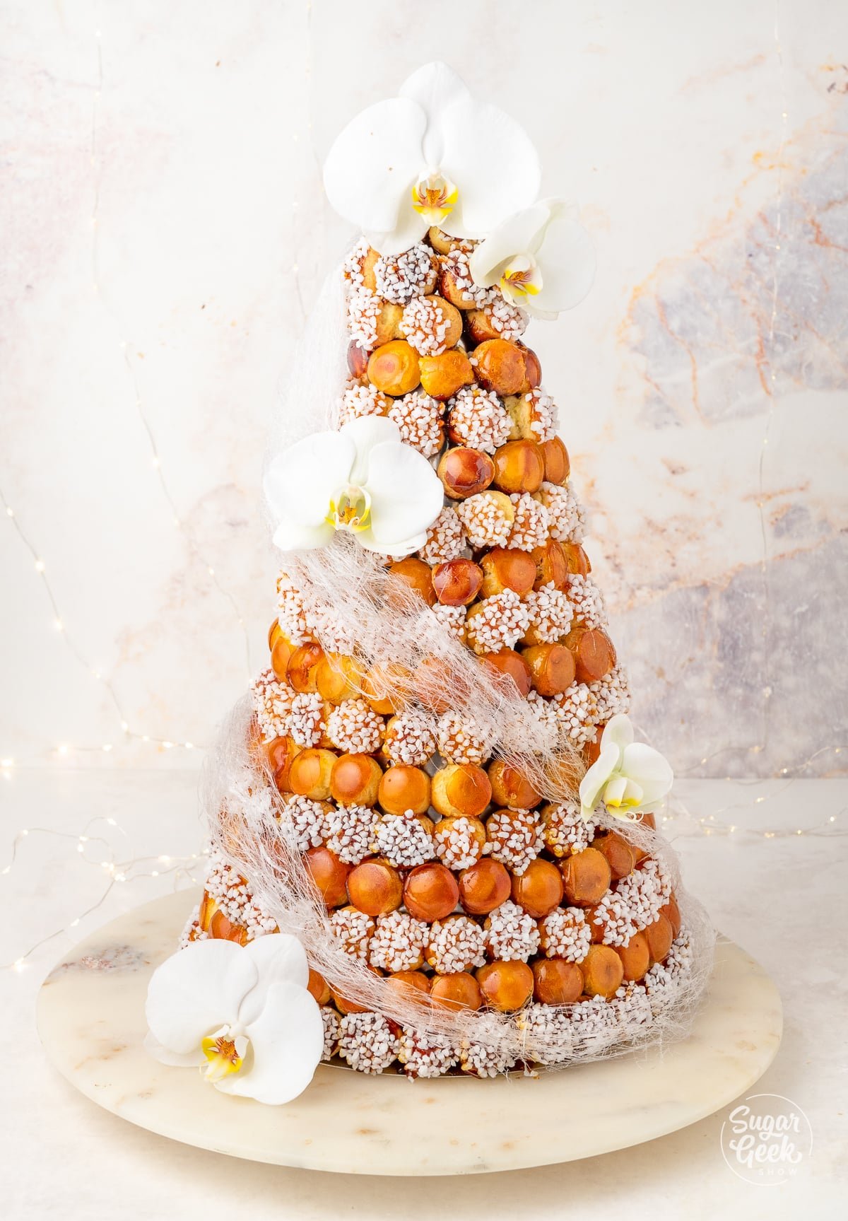 croquembouche cream puff tower decorated with spun sugar and orchids