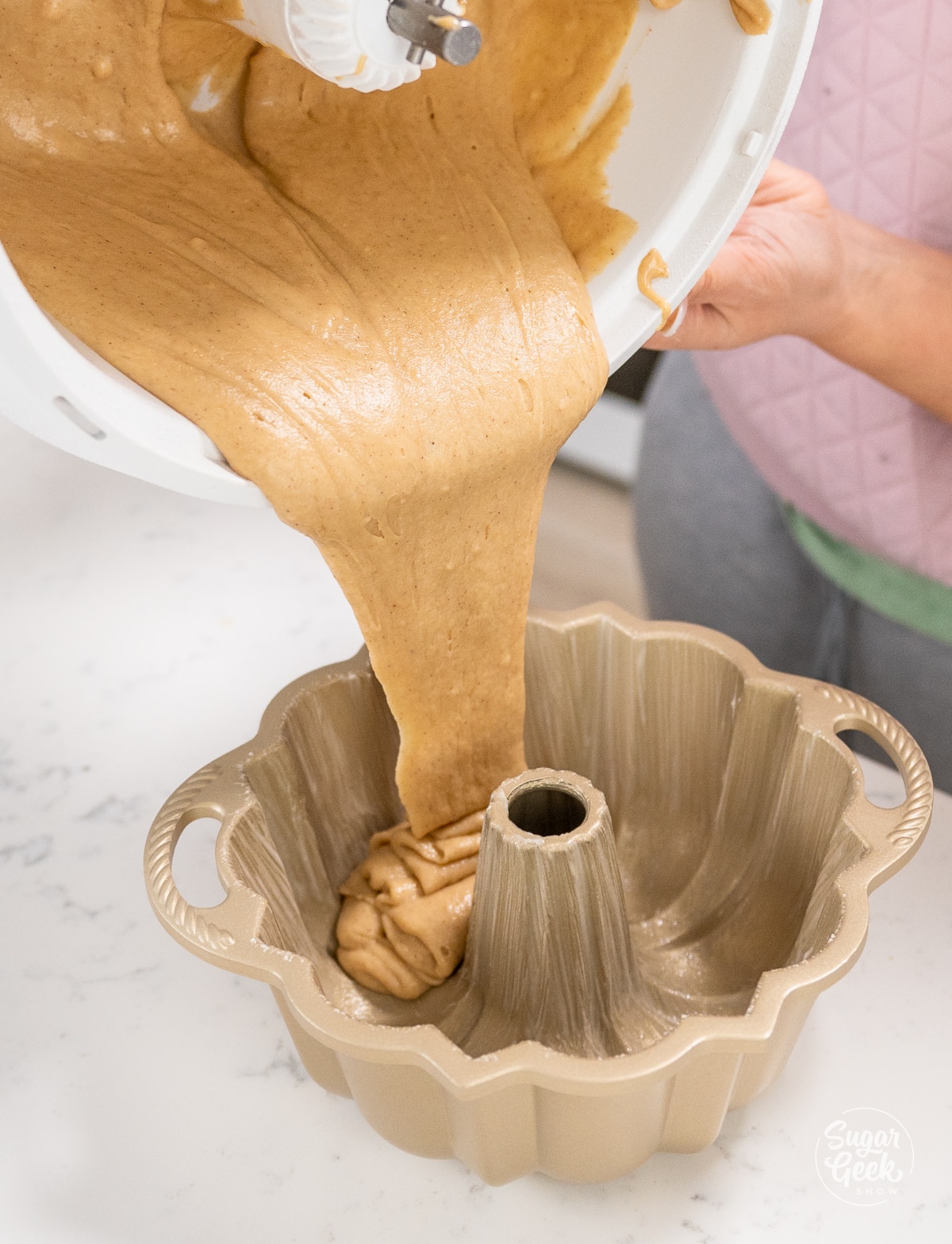 pouring honey cake batter into a bundt pan. 