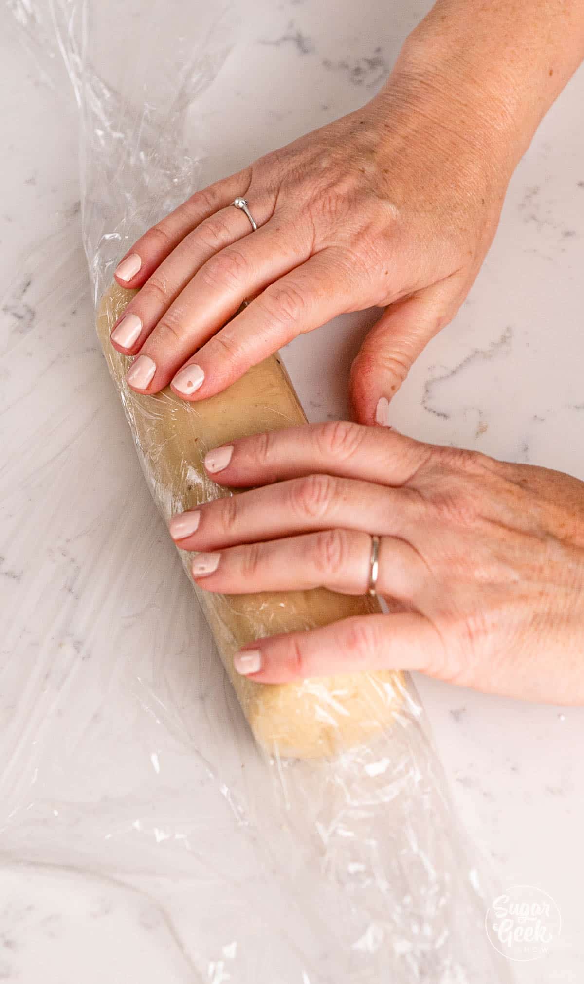 hands wrapping marzipan in plastic wrap. 