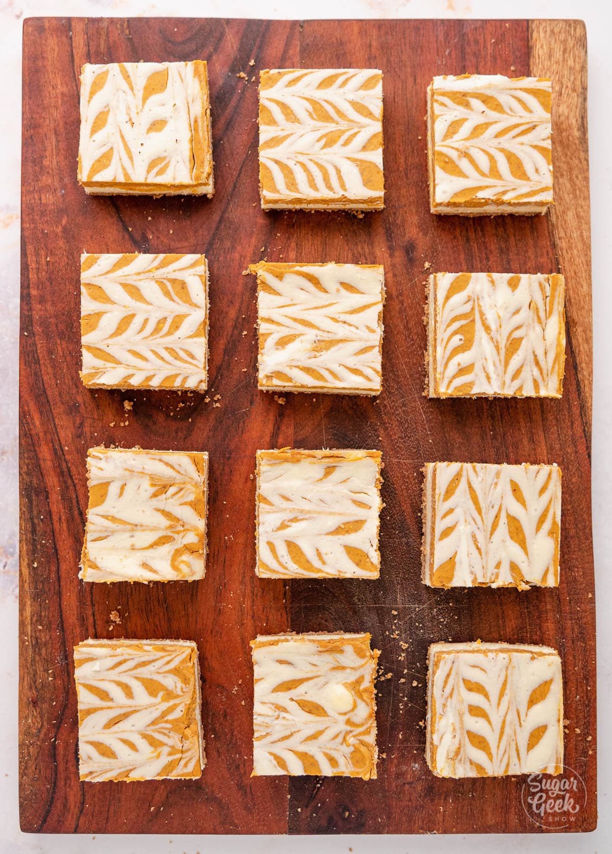 pumpkin cheesecake bars laid out on a wooden board
