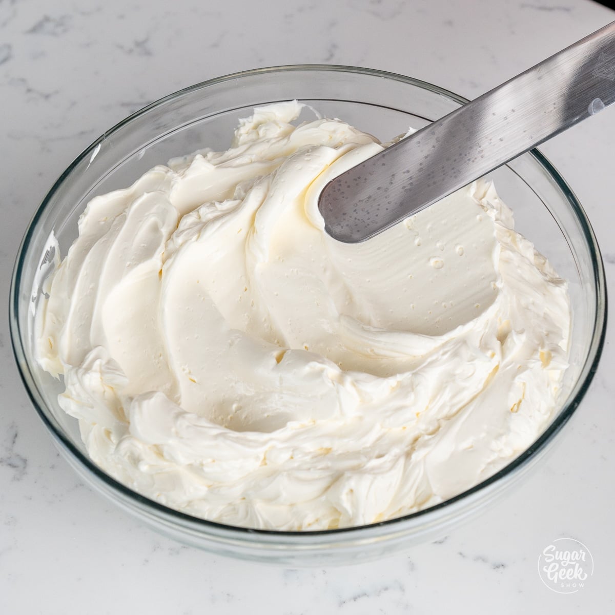 Swiss meringue buttercream in a clear bowl with a spatula.