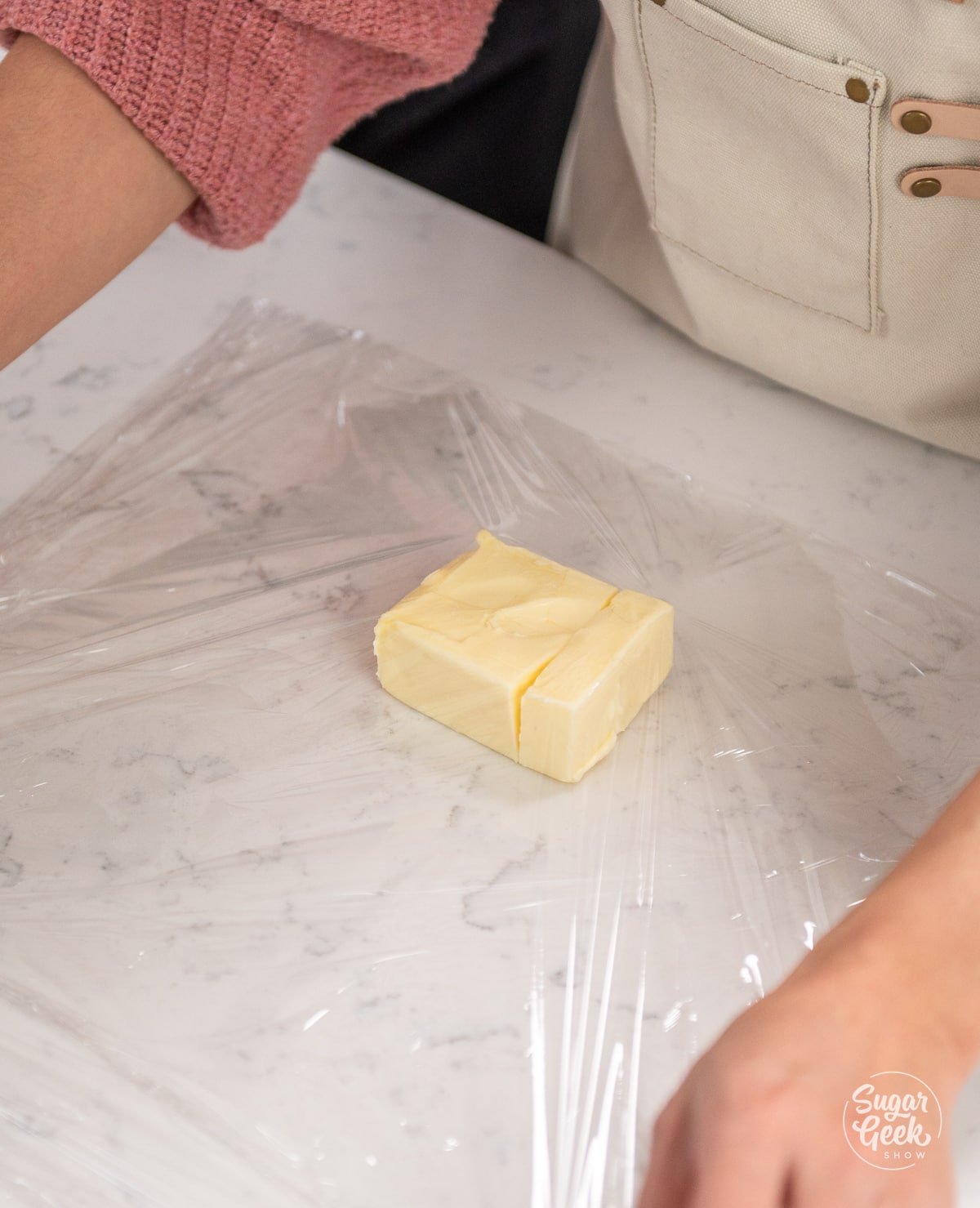 rectangle of butter laying on top of sheet of plastic wrap