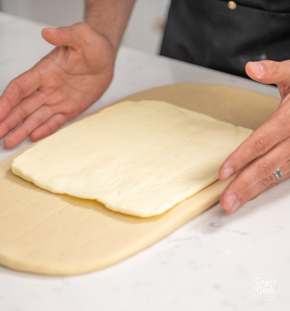 hands placing a butter block on top of croissant dough